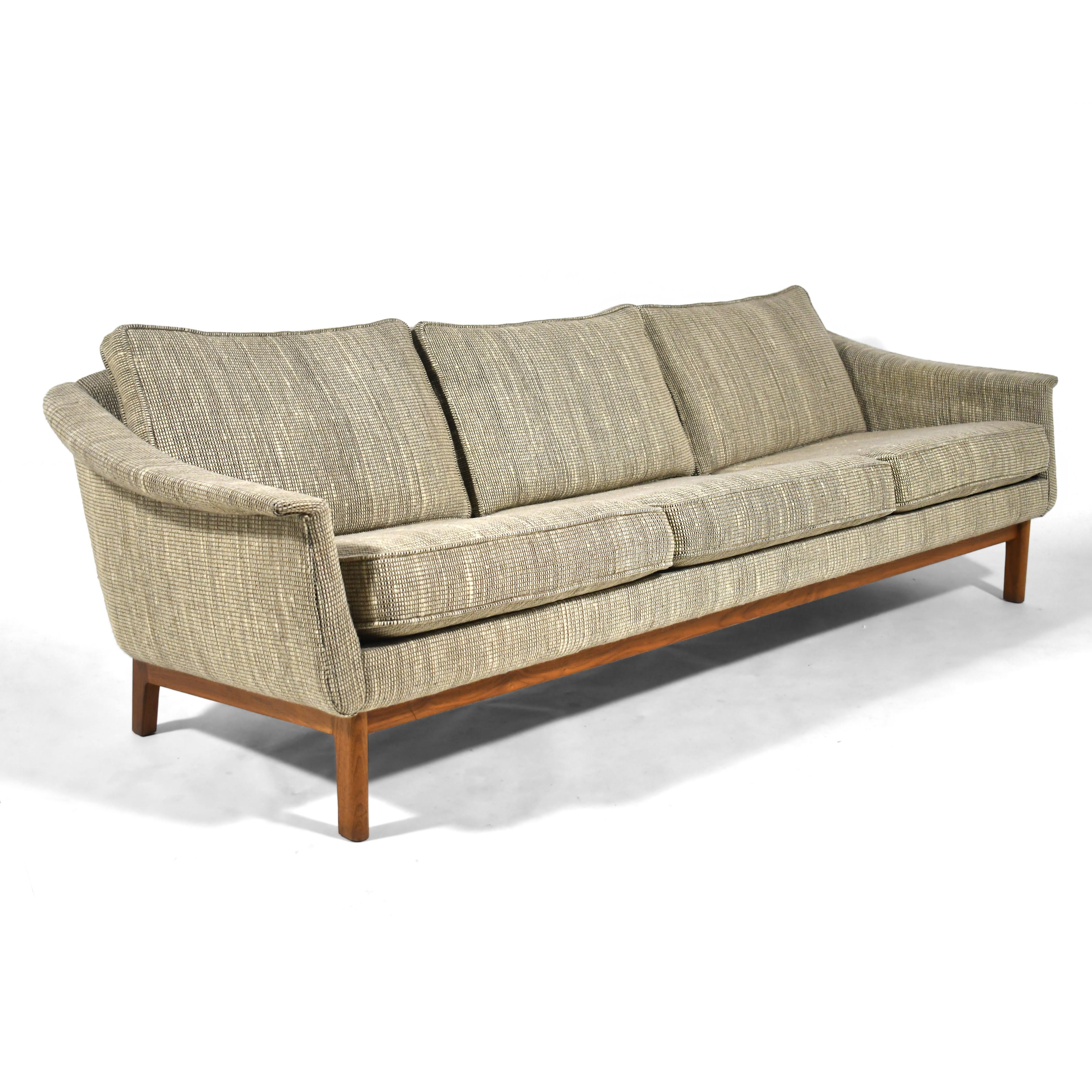 Ein schönes, subtiles Design des schwedischen Designers Folke Ohlsson, dieses  gepolstertes Dreisitzer-Sofa mit sanft geschwungenen Linien wird von einem Sockel aus Nussbaumholz getragen. Er befindet sich in einem sehr guten Originalzustand und hat
