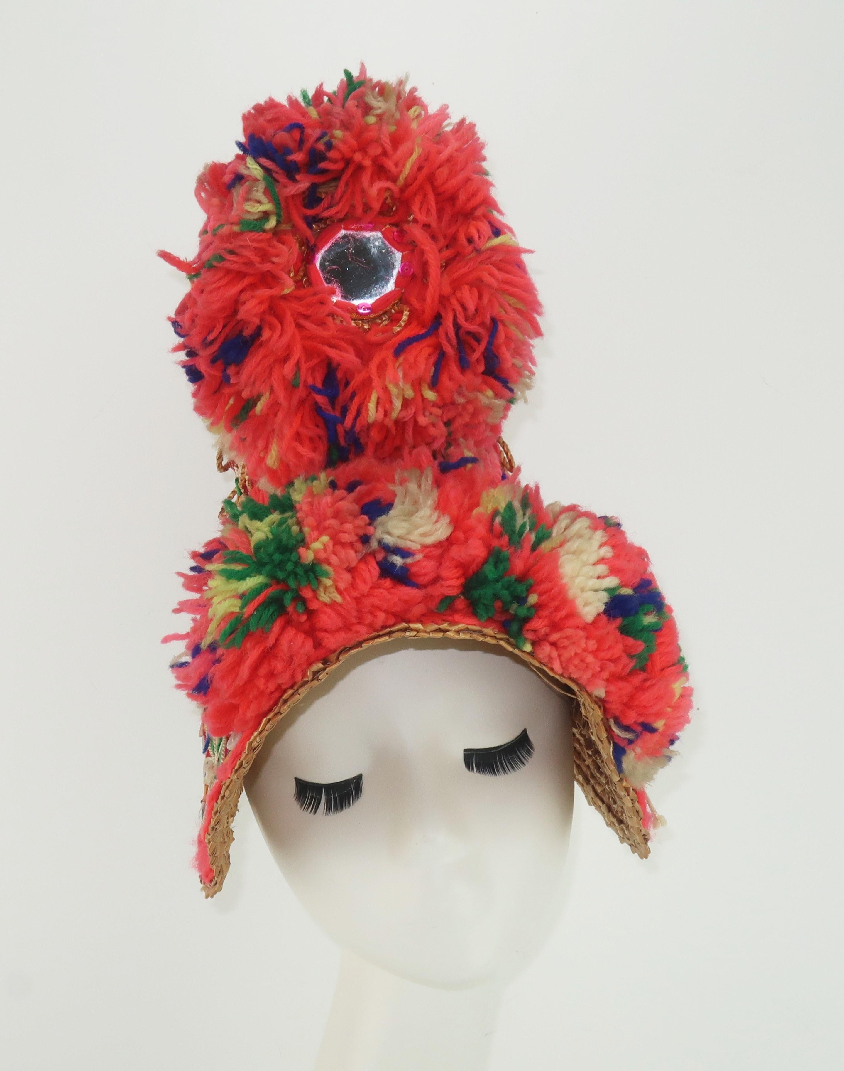 An amazing heavily embellished Spanish 1950's straw hat with an exaggerated silhouette that is reminiscent of Victorian poke bonnets.  The hat sports a tall crown with a curved brim that frames the face and is decorated with brightly colored yarn,