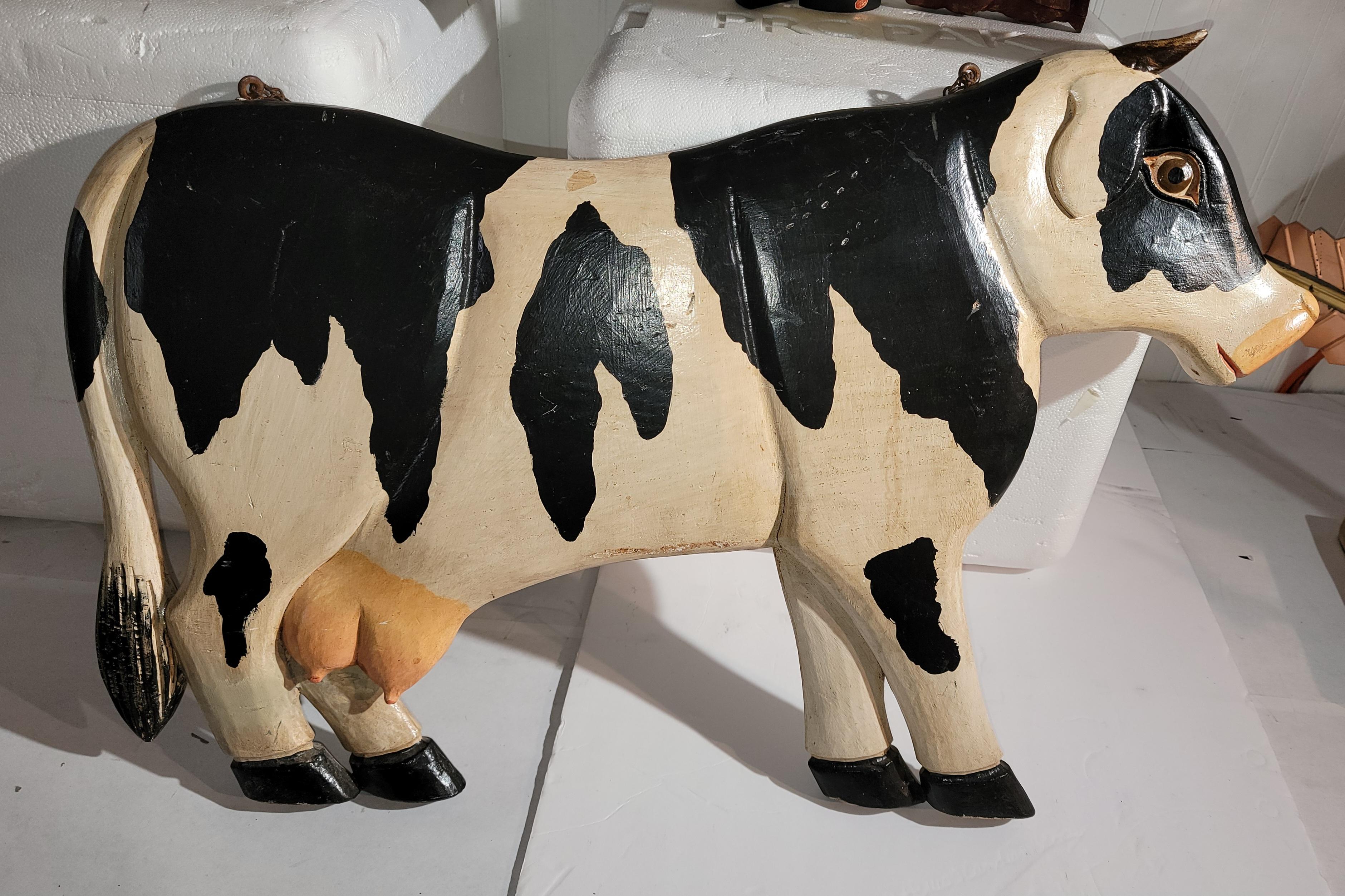 This hand carved & painted folky cow wood hanging double sided trade sign.This carved cow has the original metal chain and is in great as found condition.