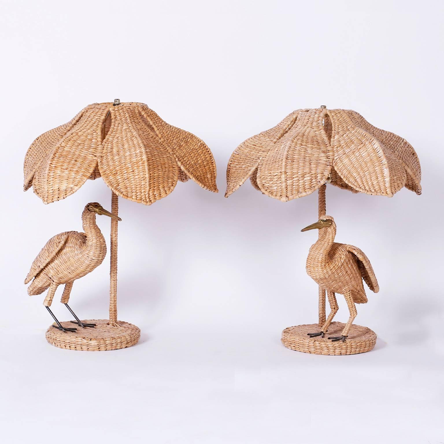 Folky and fun pair of wicker or reed egret table lamps. These birds have a brass face and beak and your choice of wicker or linen shades. Signed Mario Torres, with a brass label on the bottom.
  