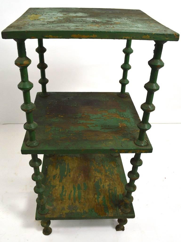 Folky and architectural spool table, in original green paint finish (finish shows significant wear) .
Three shelves (6, 20, 34 inches H), stacked spool legs, feet show loss, as shown.
Please view the other spool stand we have listed from the same