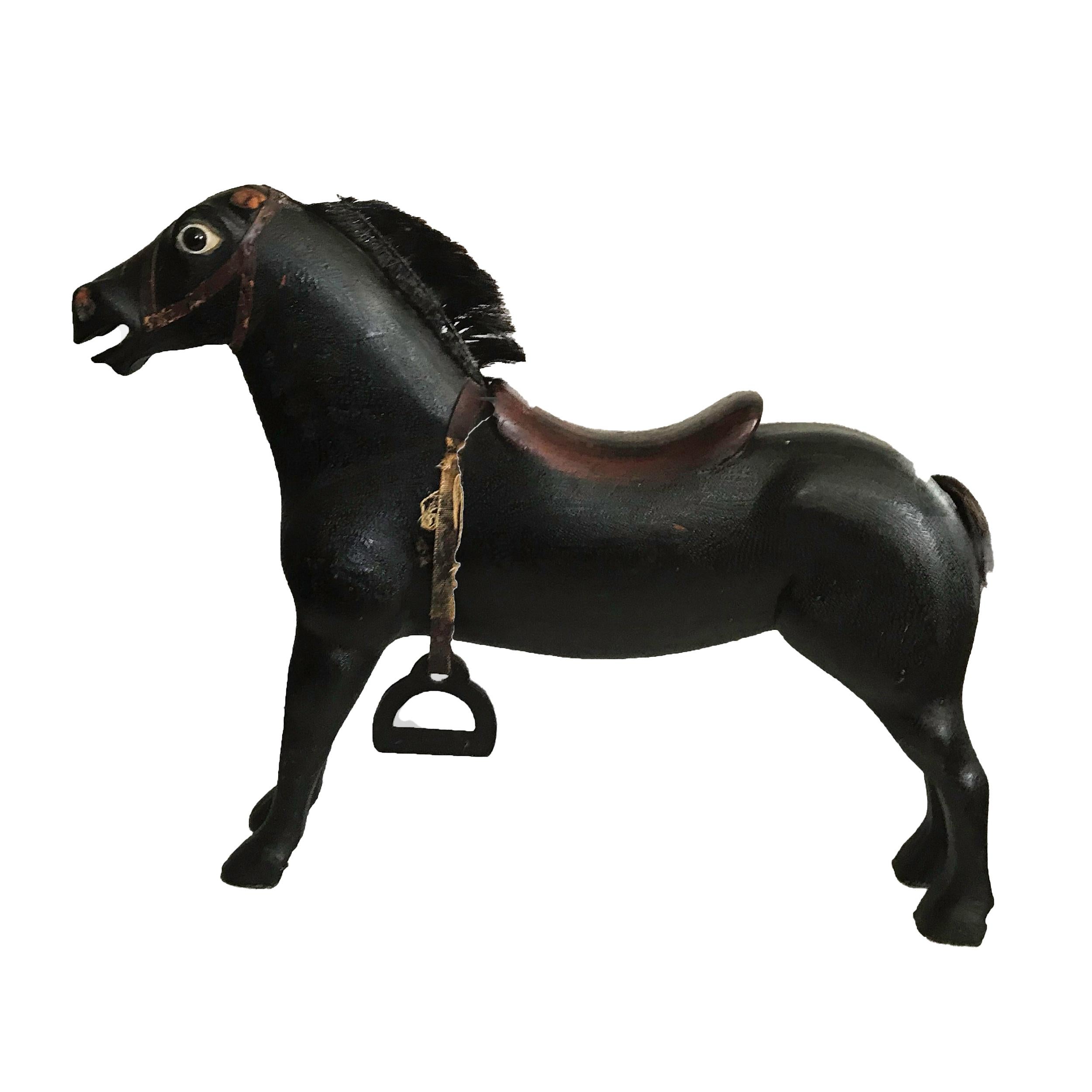 Painted black with a red saddle, glass eyes and hairm. Missing one of its stirrups, the stirrup is carved from wood and is hanging from its original thick canvas. The ears which were probably leather are missing. A strong amount of crazing indicates