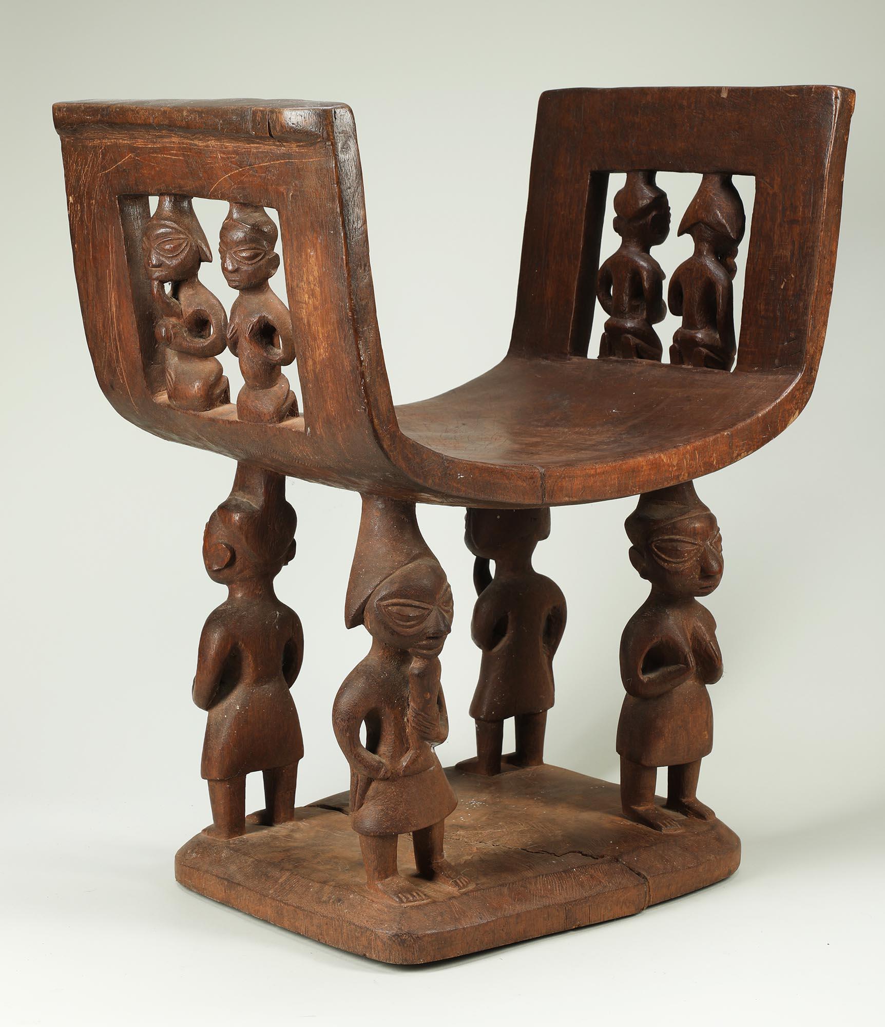 Sedile cerimoniale in legno duro intagliato con figure multiple, proveniente dal Benin, in Africa. Legno tinto scuro con aree usurate dall'uso, seduta a forma di 