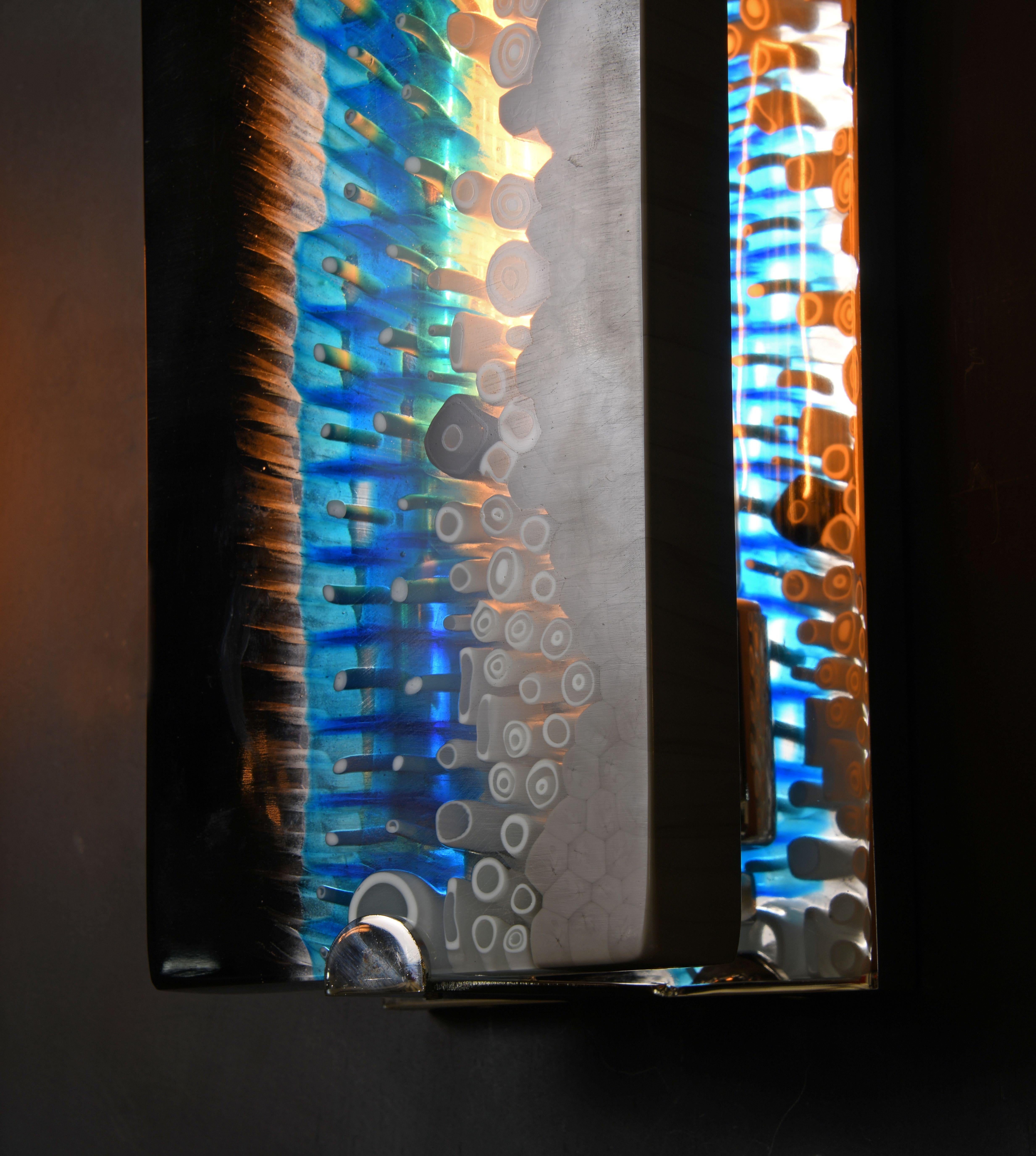 Des dalles brillamment colorées -captant la magie de l'ancien procédé du verre de Murano Millefiori de Brilliante- admirent leur reflet dans des cadres de nickel narcissique.

Les modèles de la collection sont fabriqués individuellement à la main