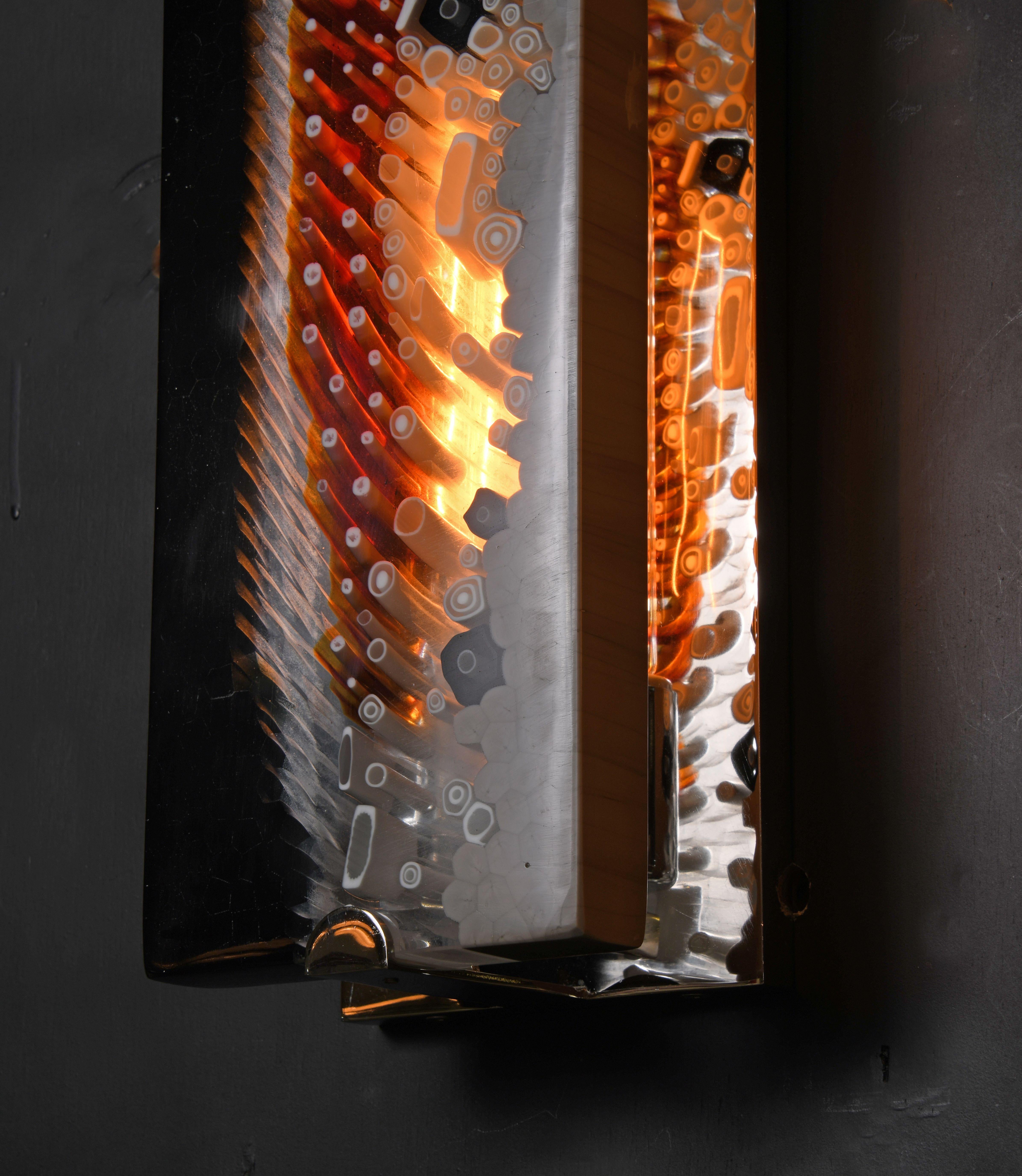 Brilliantly colored slabs –capturing the magic of the ancient process of Murrina Millefiori Murano glass – admire their reflection in frames of narcissistic nickel.

Models in the collection are individually hand-crafted by the skilled artisans in