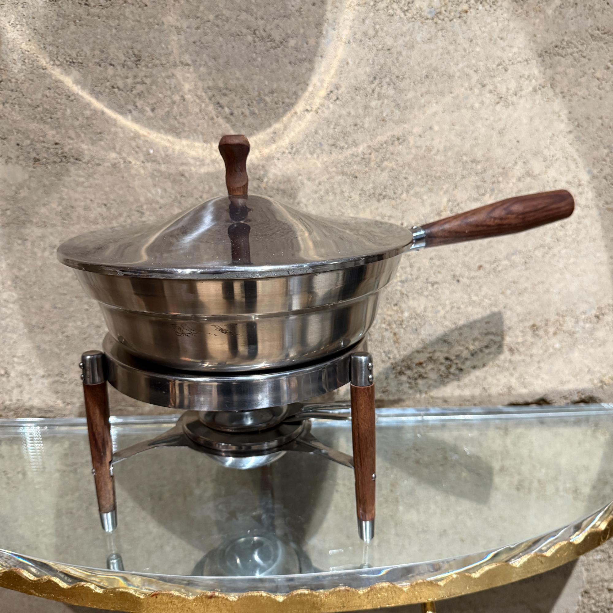 Pour votre considération, un réchaud à fondue vintage en acier inoxydable avec pieds et poignées en teck. Non marqué.

Dimensions : 11