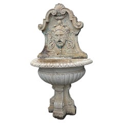 Composite stone wall fountain with mask and basin, italy