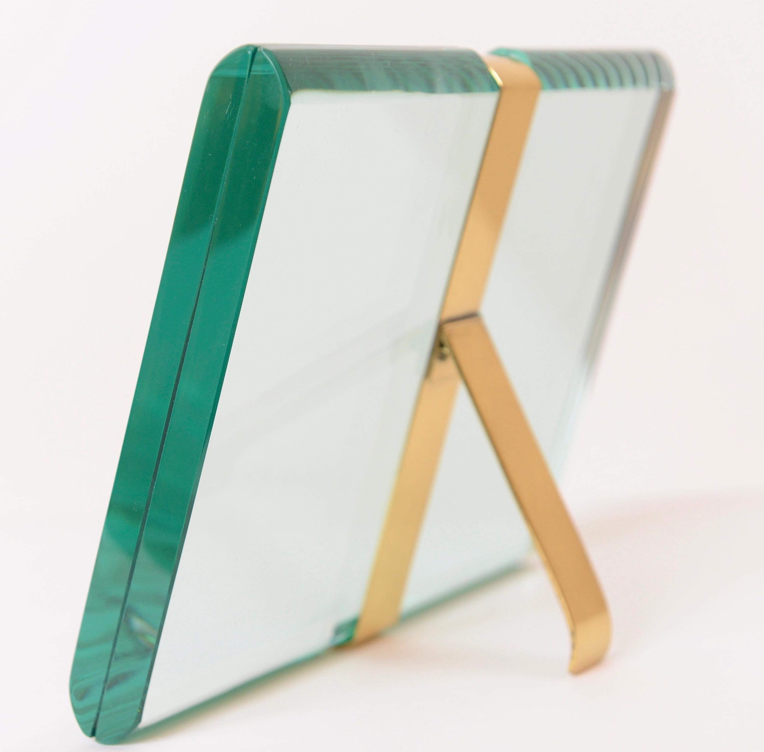 An exquisite St Gobain crystal picture frame designed and produced by the Milanese company, Fontana Arte, in 1955. The slender brass fitting and back support couples the two pieces of beveled glass enabling the user to place a photograph between