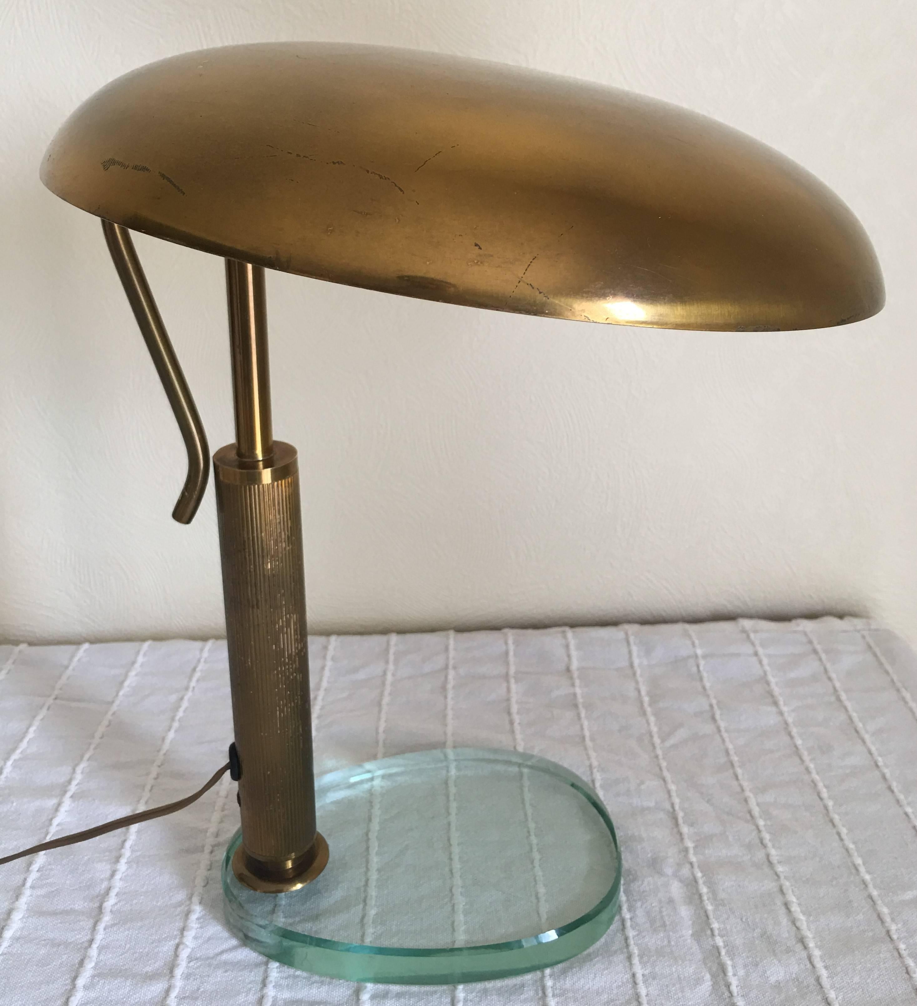 Elegant desk or table lamp produced by Fontana Arte in 1950s.
The fluted barrel and the glass base are characteristic elements of Fontana Arte's production.
The brass reflector is adjustable thanks to the long handle at the backside
Very beautiful