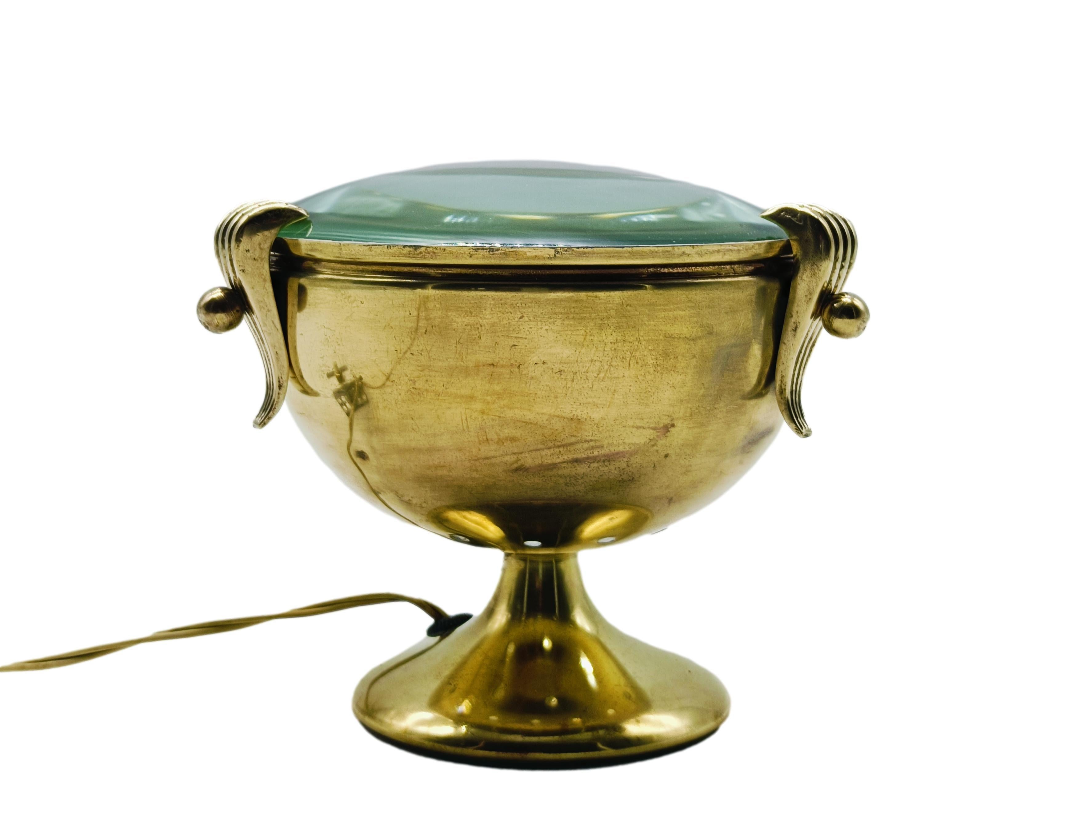 Caratteristica lampada da tavolo anni '50 a calice in ottone. Supporto a sezione circolare poggiante su piede lievemente svasato, riflettore a lente in vetro molato che diffonde la luce verso l'alto