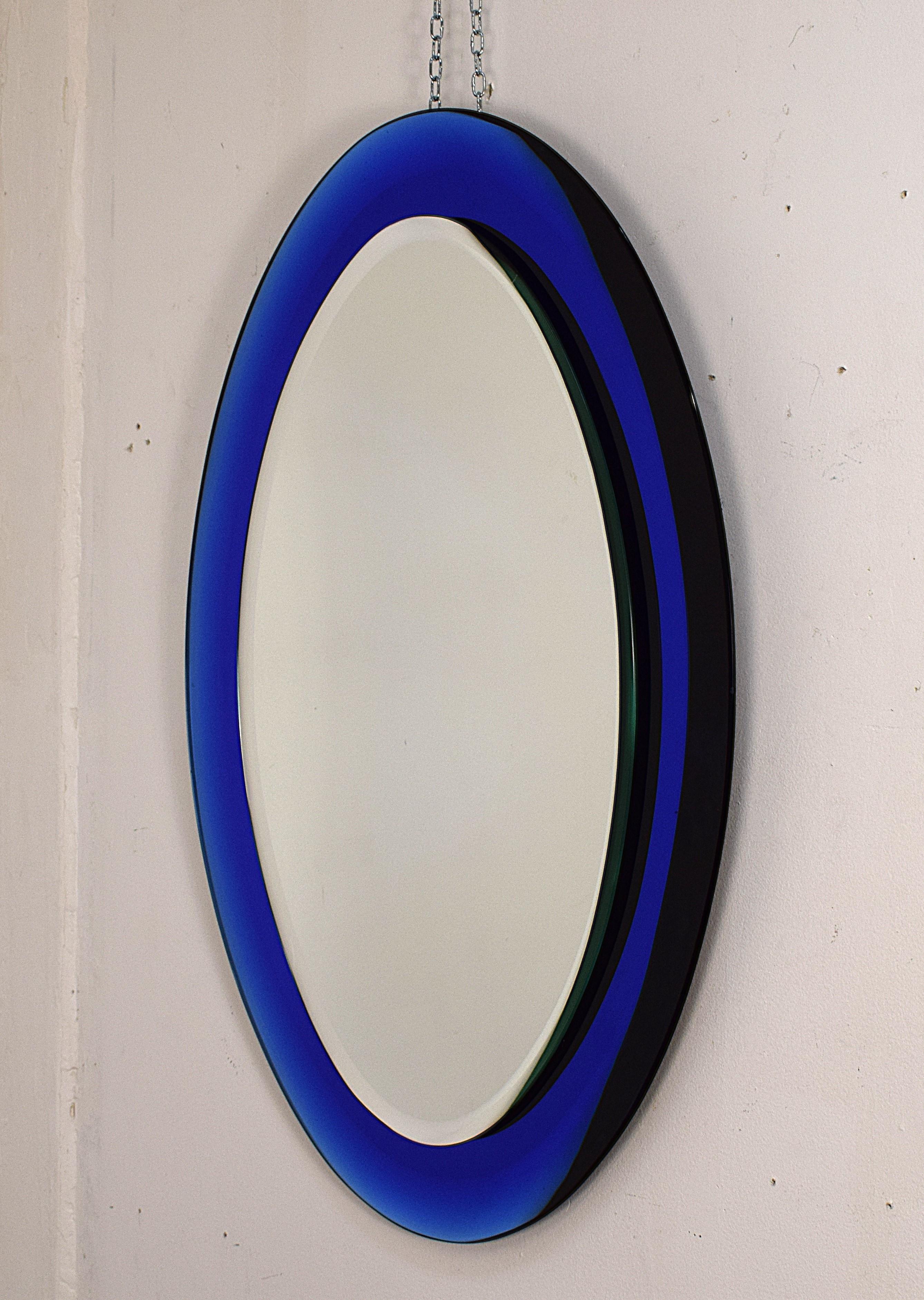 Specchiera ovale attribuita a Fontana Arte, anni ’60, dal design elegante e senza tempo. Realizzata in vetro specchiato e vetro colorato, questa raffinata specchiera si distingue per la cornice sfumata blu cobalto che conferisce profondità e
