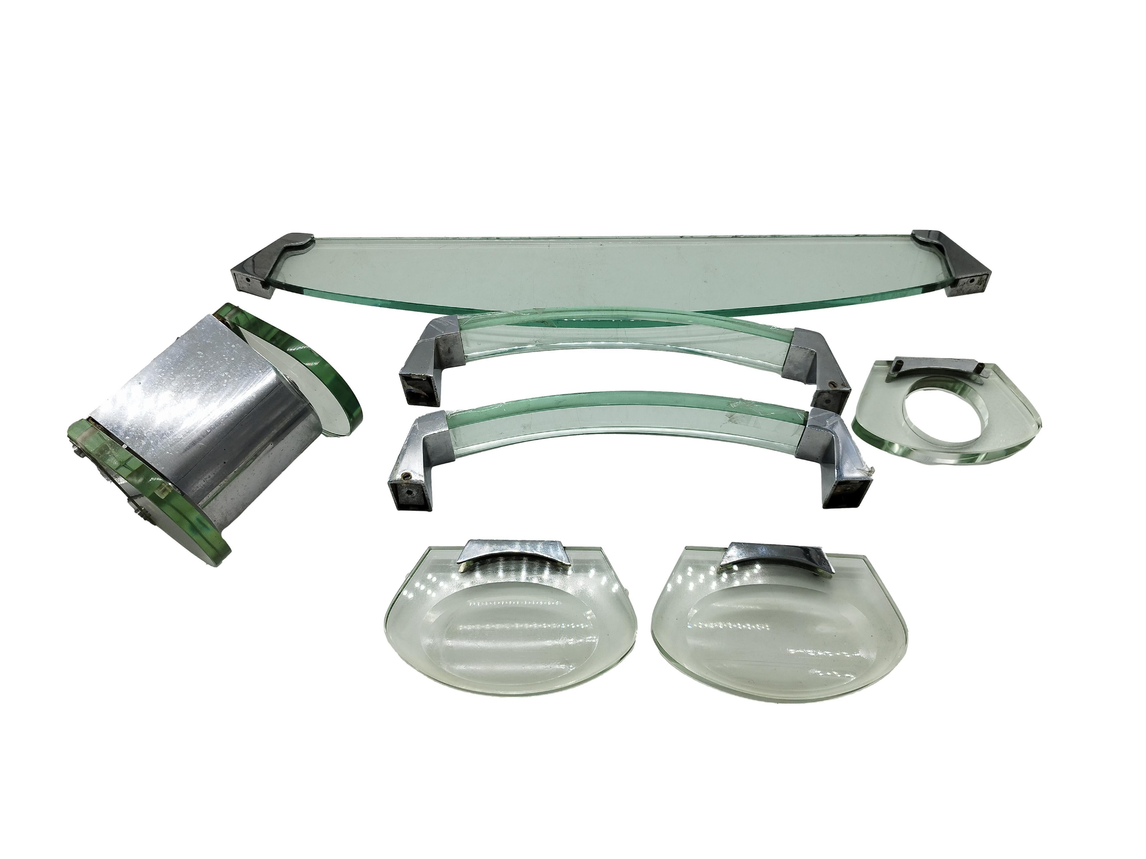  Questo set da bagno di Fontana Arte è realizzato con uno spesso vetro smussato e giunti in ottone nichelato. È composto da 7 accessori diversi: 1 ripiano grande (cm. h.1x66x26), 2 porta asciugamani (cm. h.4x37x8), 1 porta Rolle (cm.h.12x16x11), 2