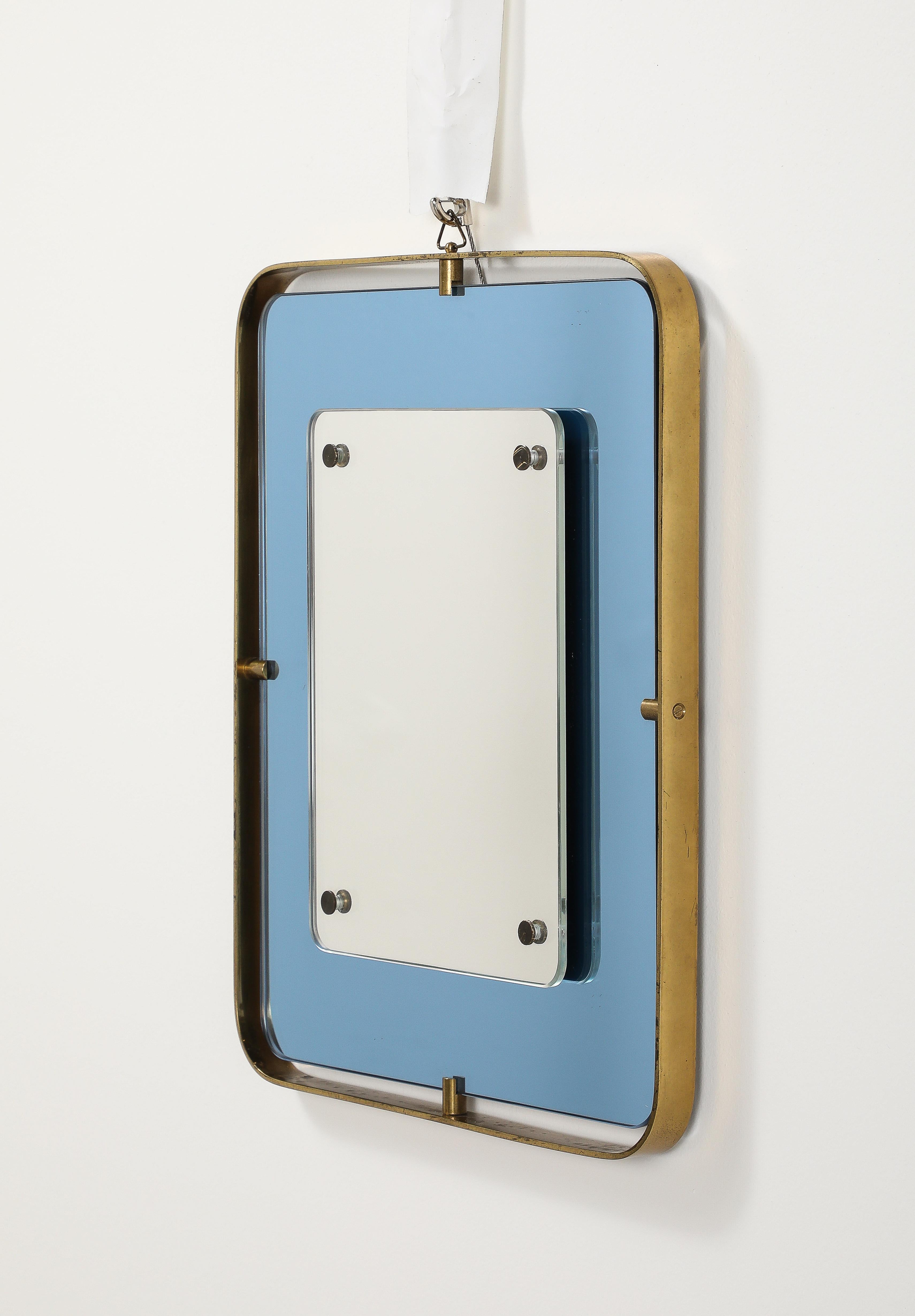 A Fontana Arte blue glass and brass wall mirror; exuding charm and grace in a simple and refined design; with a clear rectangular mirror plate in the center, a magnificent blue colored glass surround and brass frame.  
By Fontana Arte, Italy circa