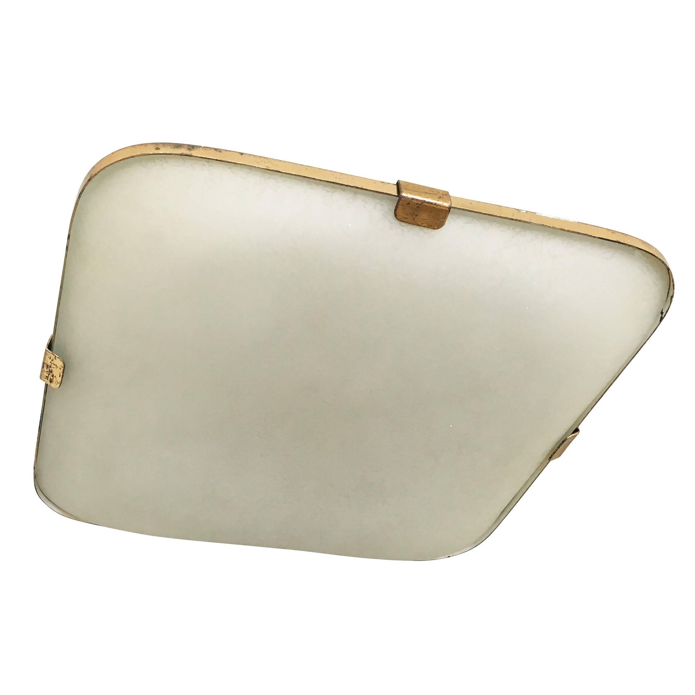 The refined taste of Max Ingrand can be seen in this elegant yet simple flush mount by Fontana Arte. The midcentury fixture features a frosted and textured glass which is framed with a thin brass rim. The organic texture of the glass, hard to fully
