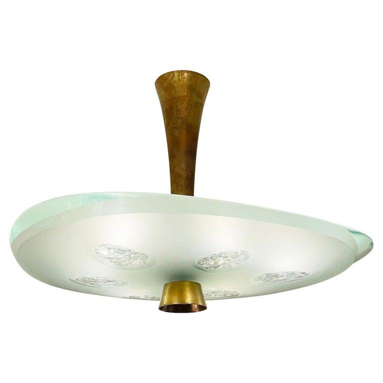 Fontana Arte ceiling light model 1748 designed by Max Ingrand in the 1950s. Features a beautiful thick glass shade with beveled edges which has been chiseled in six irregular areas. Holds six candelabra bulbs. Two available.

Condition: Excellent