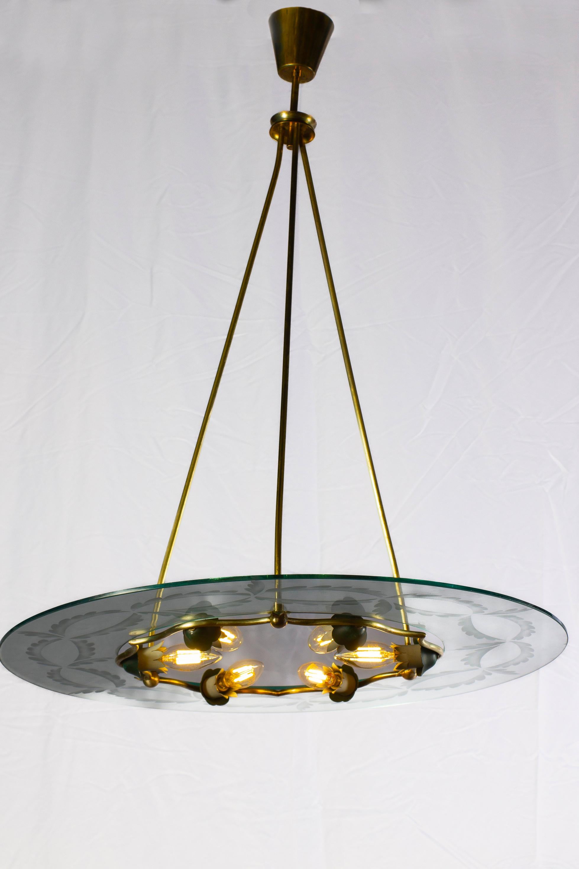 Amazing pendant with finely hand chiseled glass with hibiscus motifs. Elegant brass frame in excellent vintage condition. The disc centered by six  E 14 light bulbs, up to 40 watts per bulb.
This piece is attributed to Fontana Arte designed by