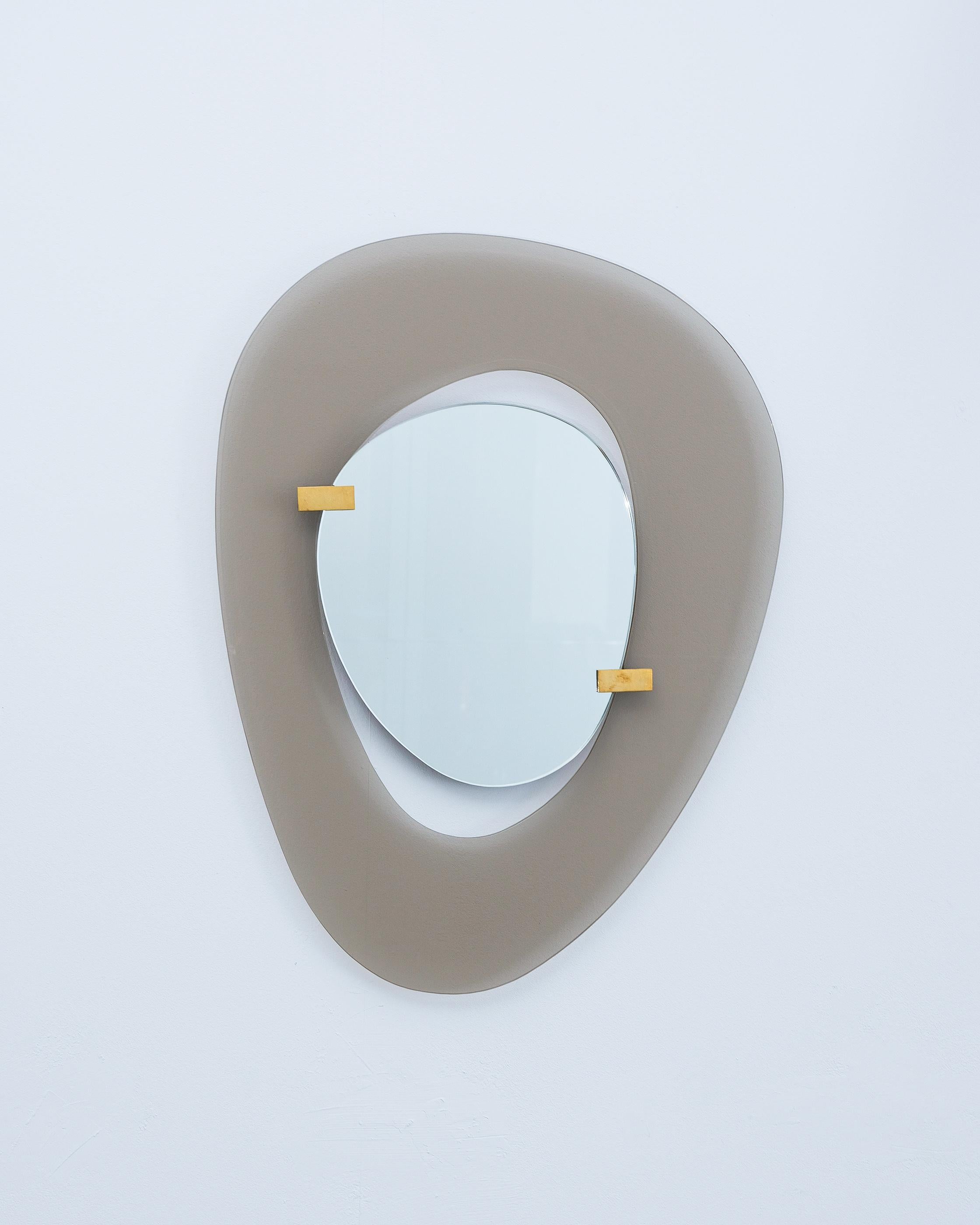 Miroir de Fontana Arte par Max Ingrand, Italie, vers 1958. Magnifique miroir avec un cadre en verre lisse gris et fumé anomique et un miroir flottant anomique fixé par deux fermoirs en laiton. Bon état, pas d'éclats, quelques rayures minimes, peu ou