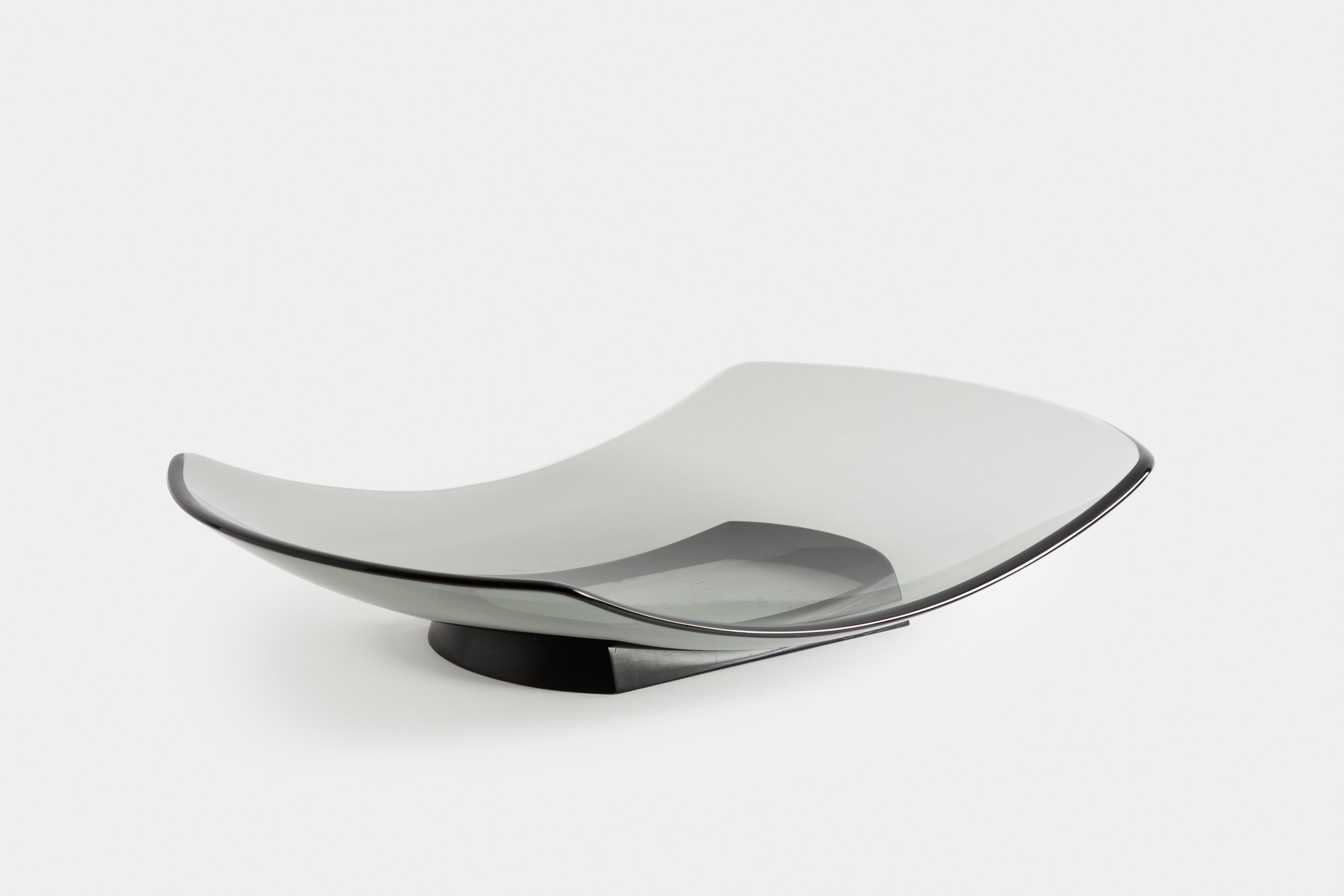 Fontana Arte large gray glass dish or centerpiece with profiled and curved glass resting on an angular fitted black enameled metal base, Italy, c. 1956.  This gray glass is a rare colorway in this model and the form is quite elegant in its curved
