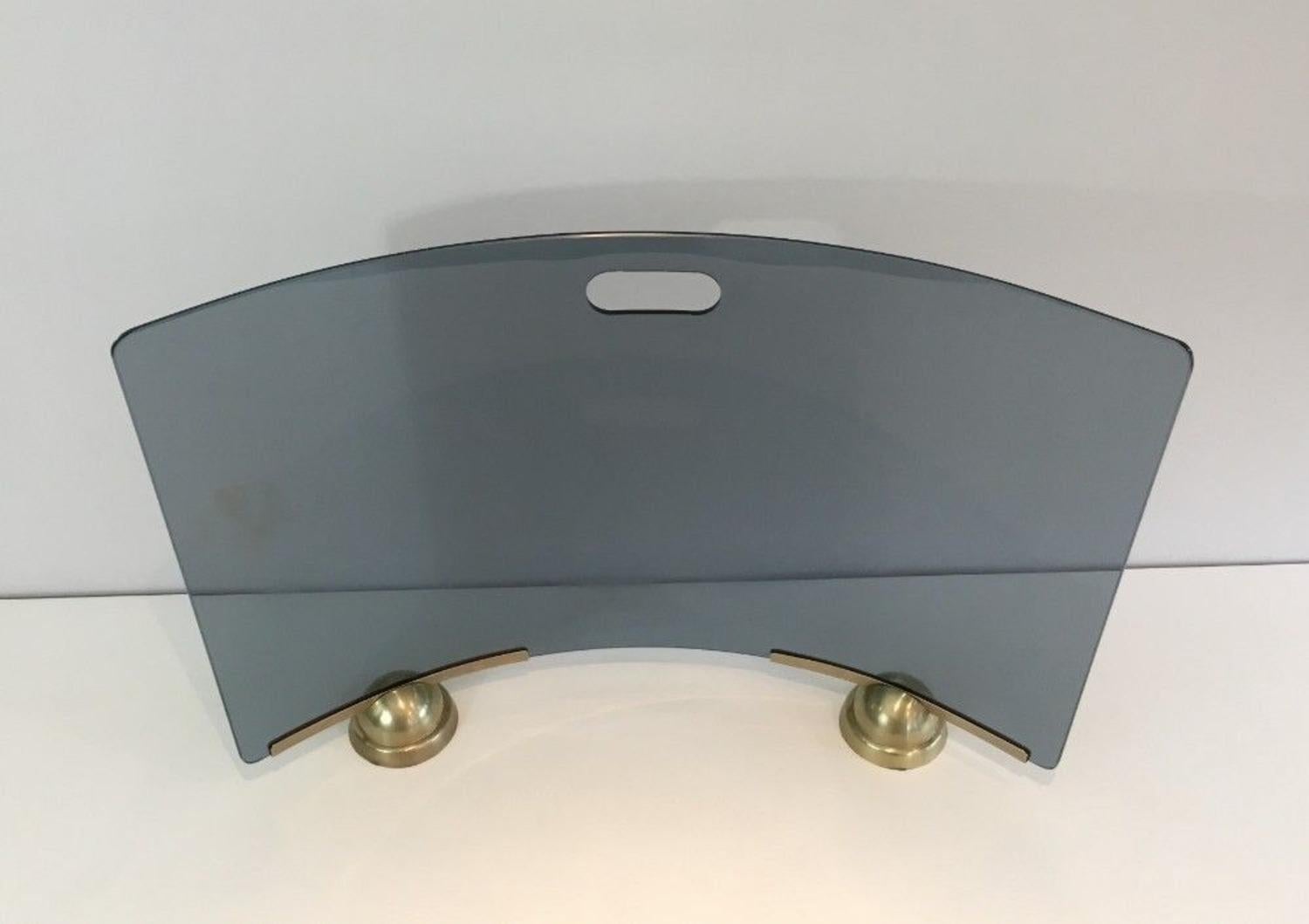 Esta bonita pantalla curvada para chimenea está formada por una base de latón y una pantalla de cristal curvado azul. Obra del famoso diseñador italiano Fontana Arte, hacia 1970.