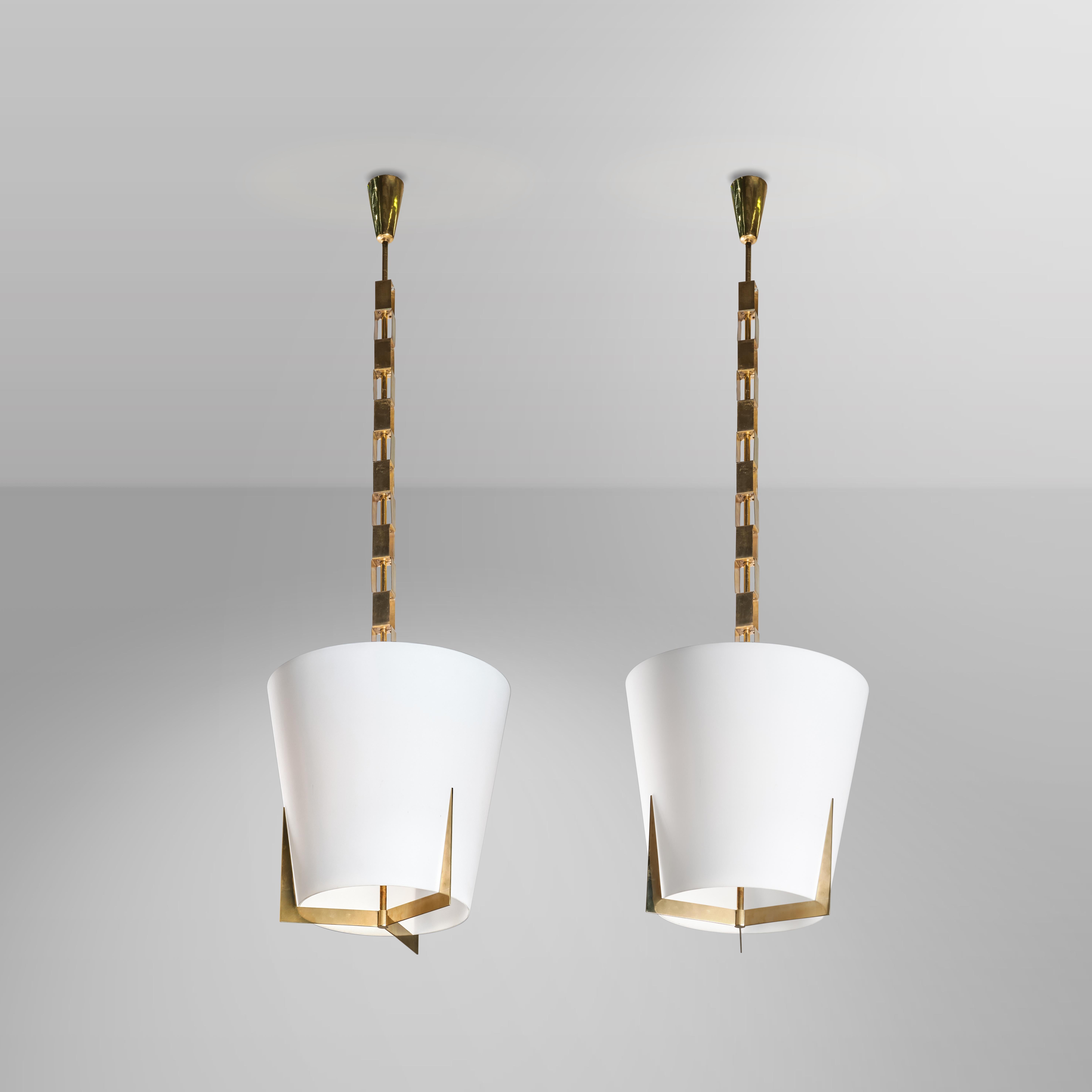 Two fantastic hanging lamps with brass structure and opal glass diffuser, typical of Fontana Arte's production and models of the 1960s. This pair of pendant lamps are as simple as they are decoratively appealing: they make elegance their strong