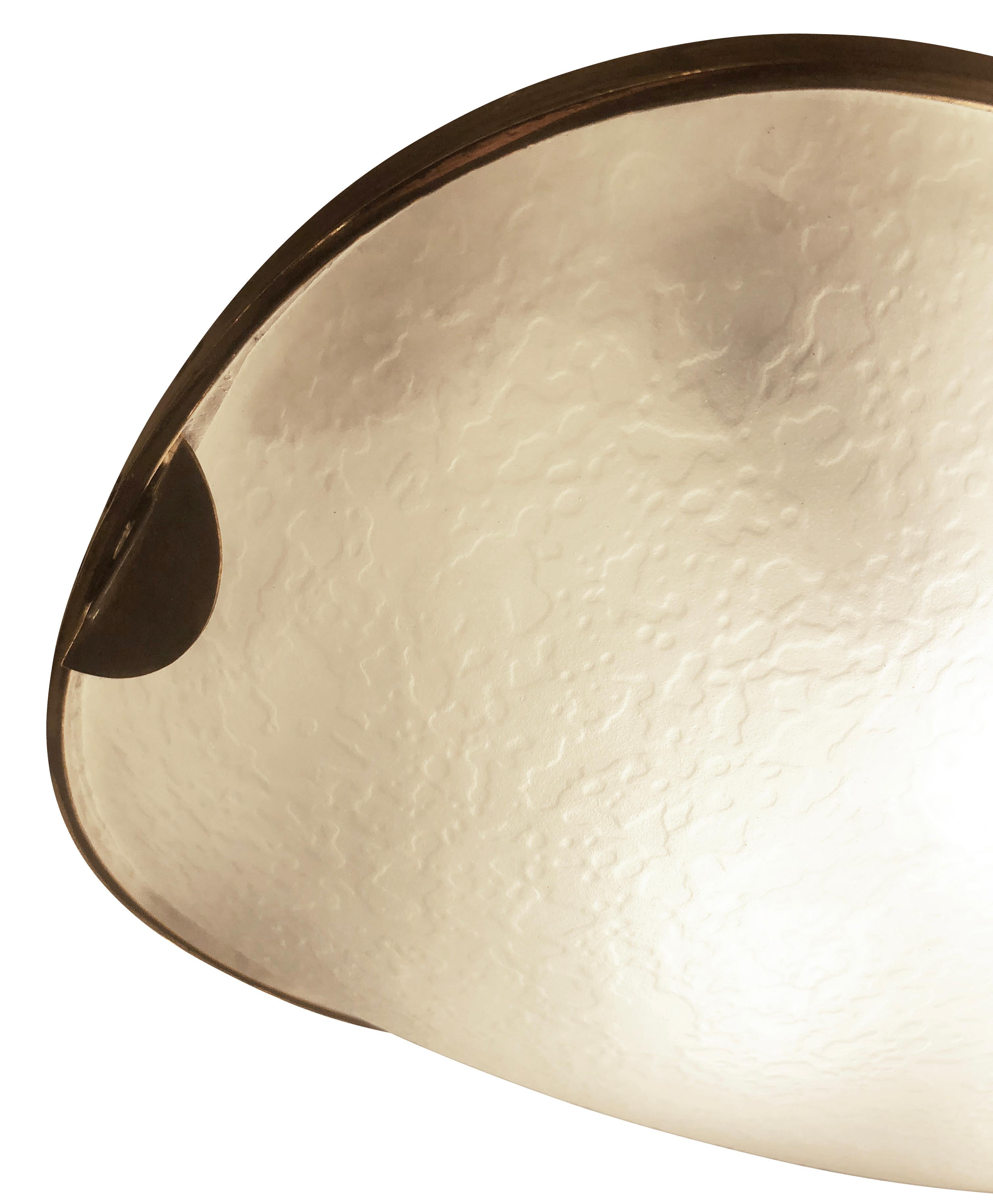 1960s racetrack flush mount or sconce by Fontana Arte featuring a frosted and textured glass which is framed with a thin brass rim. The texture of the glass, hard to fully grasp in pictures, hides the internal structure with its four candelabra