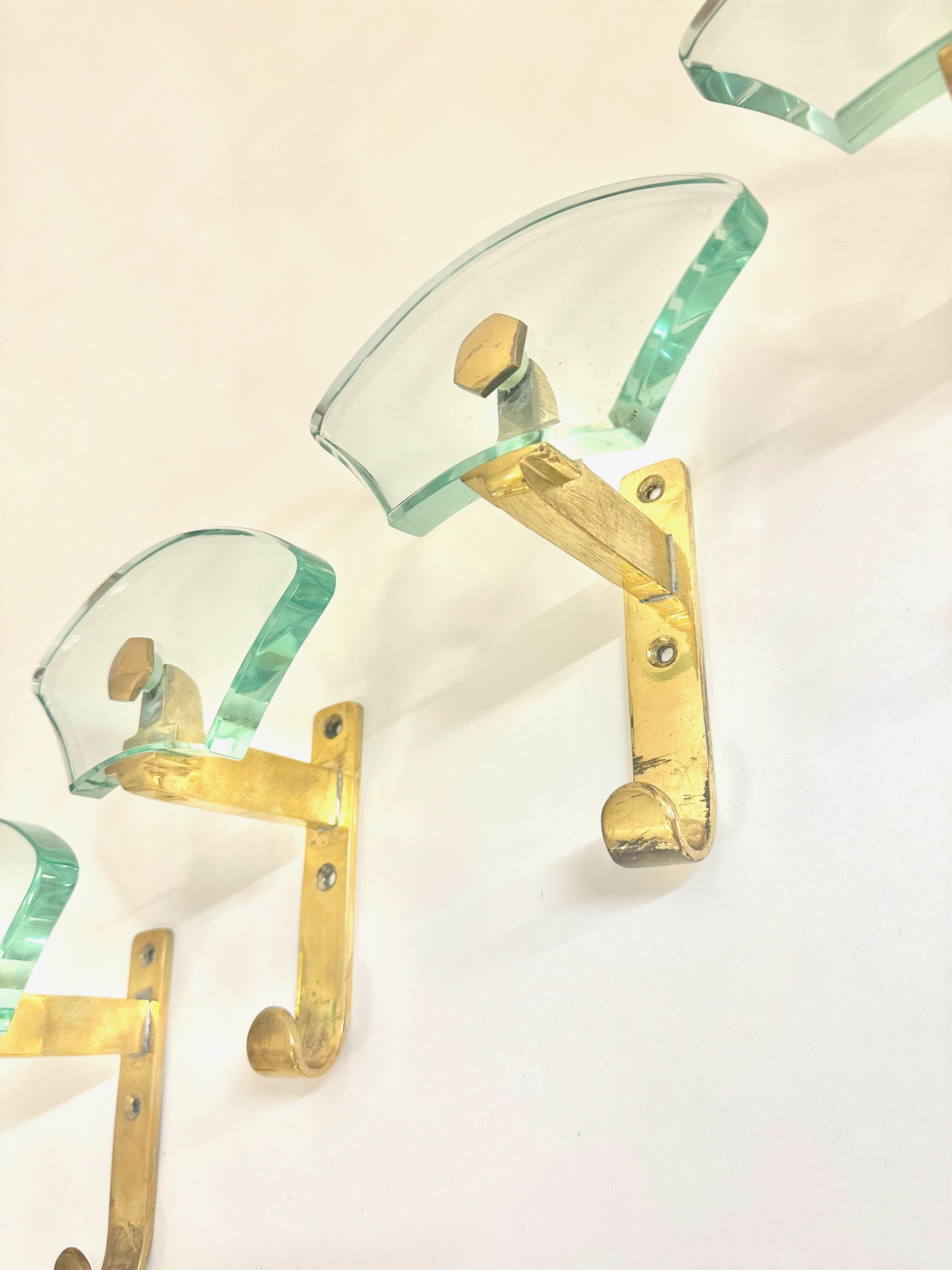 Un ensemble de  Quatre porte-manteaux muraux en laiton et verre de la marque Fontana Arte, en excellent état.
Emballage et expédition gratuits .