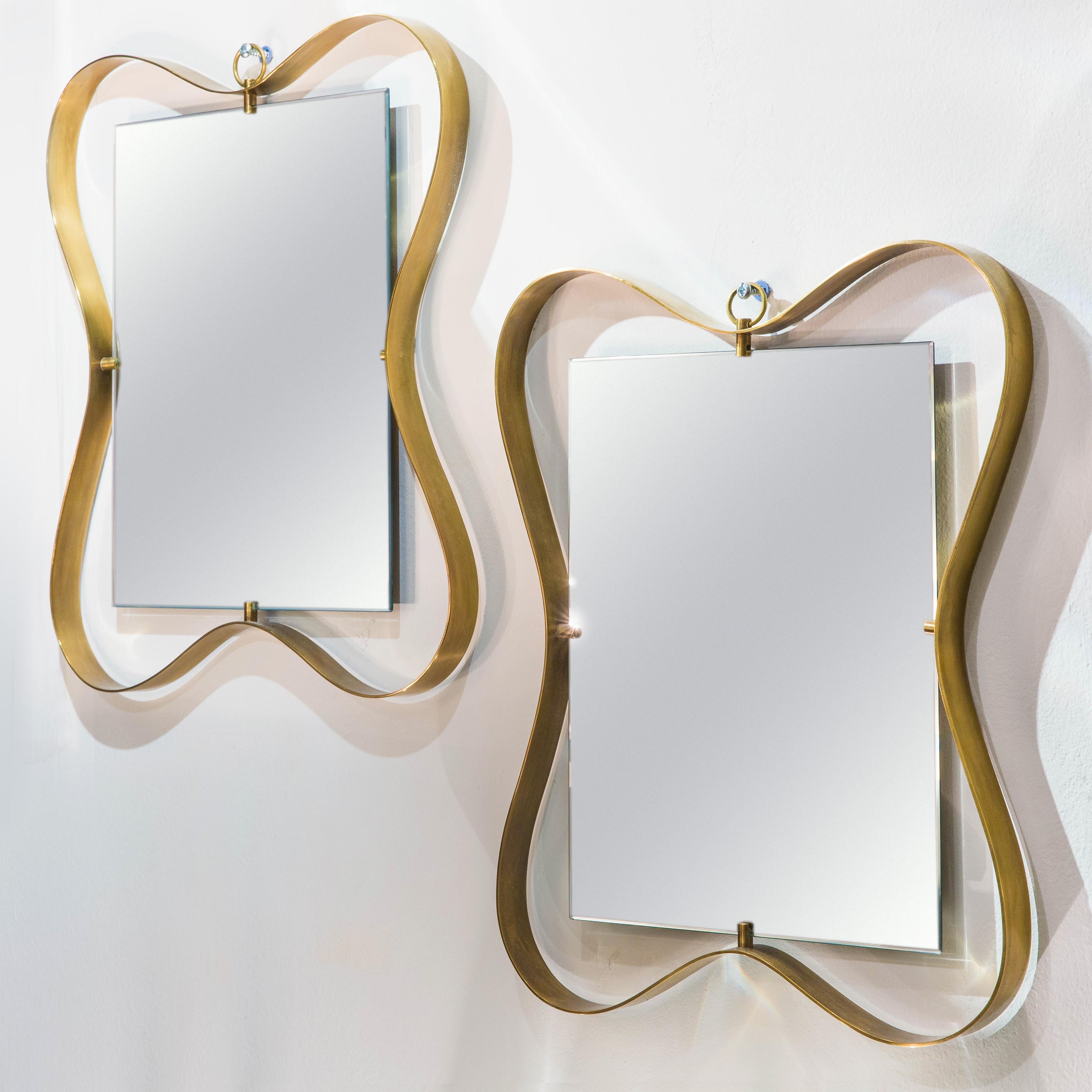 Fontana Arte pair of whimsical and elegant mirrors with curved patinated brass frame holding beveled mirrored glass, Italy, circa 1950.

Second mirror is available to make a pair.

Literature
Lastre di Vetro e Cristallo, No. 10, August 1950