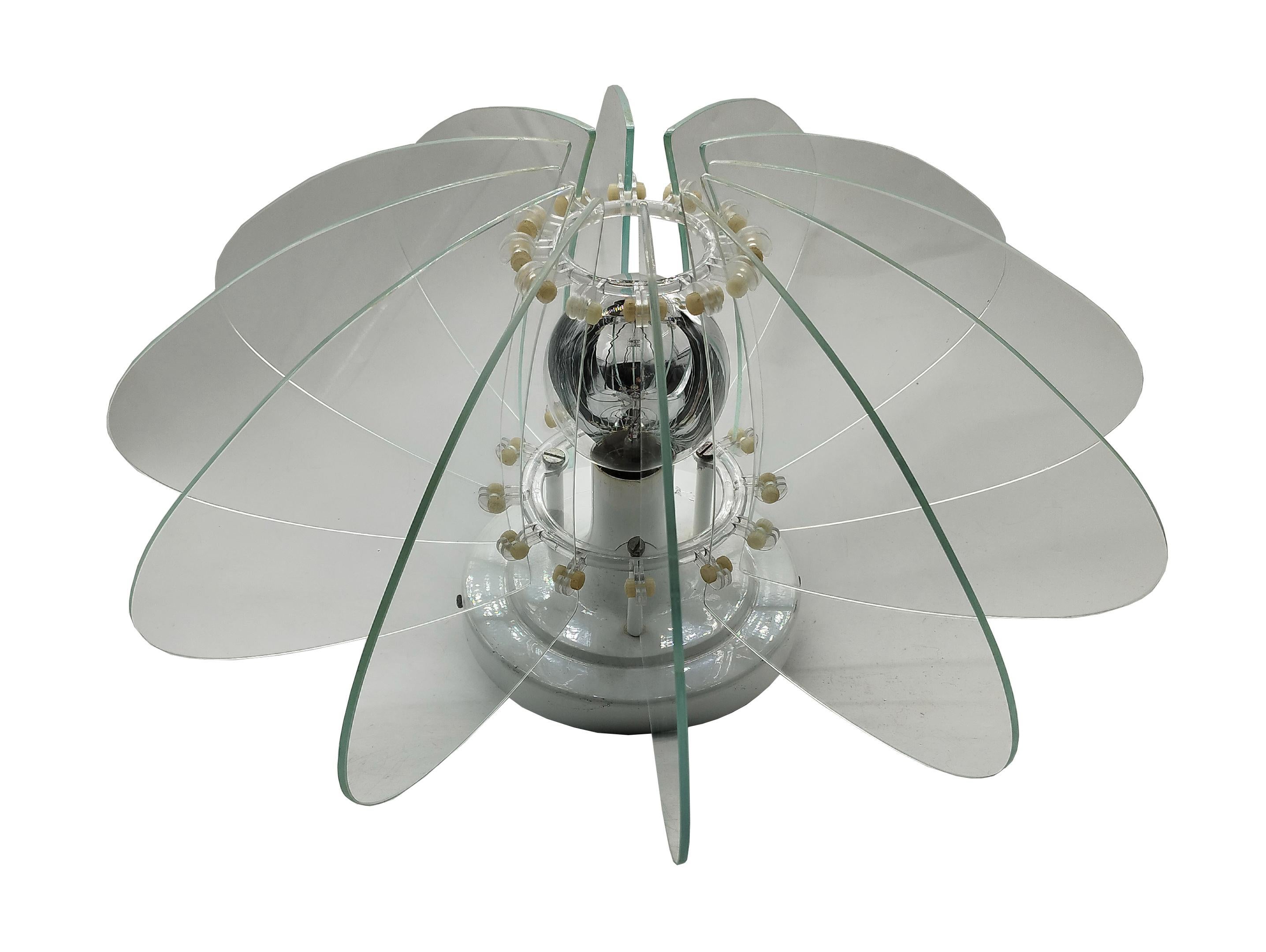 This chandelier is reminiscent of the works of Gae Aulenti and Fontana Arte. It features 12 wedges of nile green glass attached to a white painted metal base with plastic rings It can be mounted either ceiling or wall.
