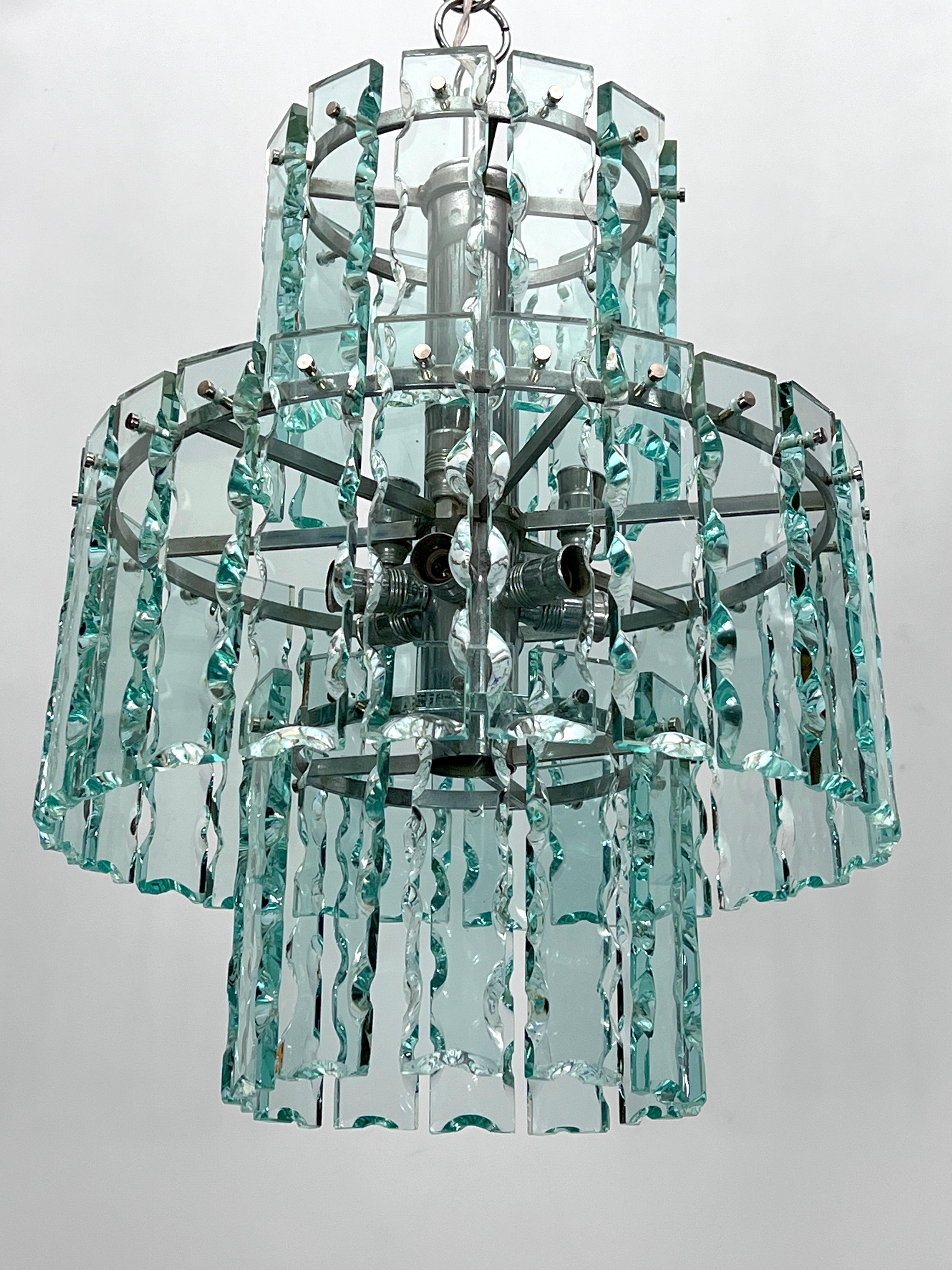 Kronleuchter aus dickem geschliffenem Glas, hergestellt von Zero Quattro in den 70er Jahren, in gutem Vintage-Zustand mit normalen Alters- und Gebrauchsspuren; einige kleine Chips in der Nähe der Schrauben. Die Struktur ist aus verchromtem Messing