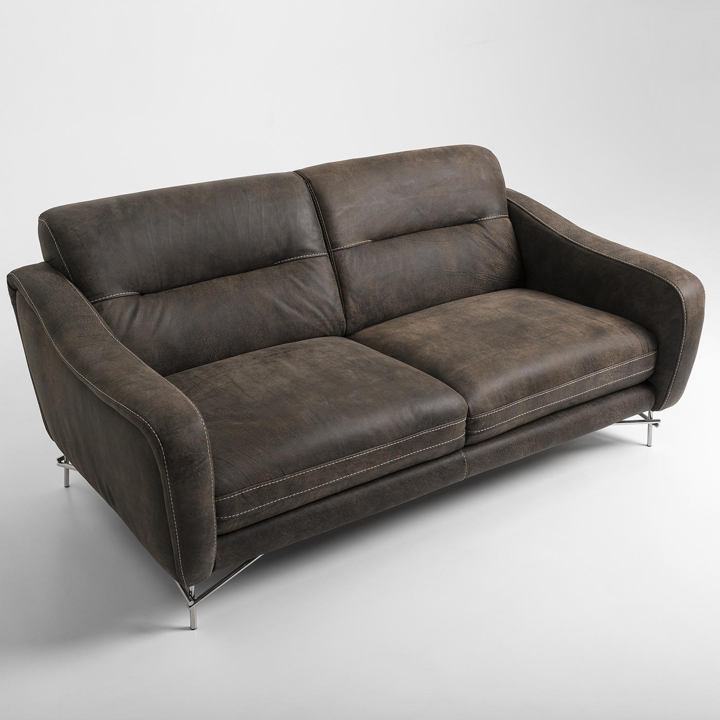 The Fonzie 2-seat sofa fuses style with comfort, boasting a modern interpretation of a Classic 1960s style. Crafted from smooth brown leather, this sofa boasts a distressed look for a subtle vintage allure. Intricate contrast stitching highlights