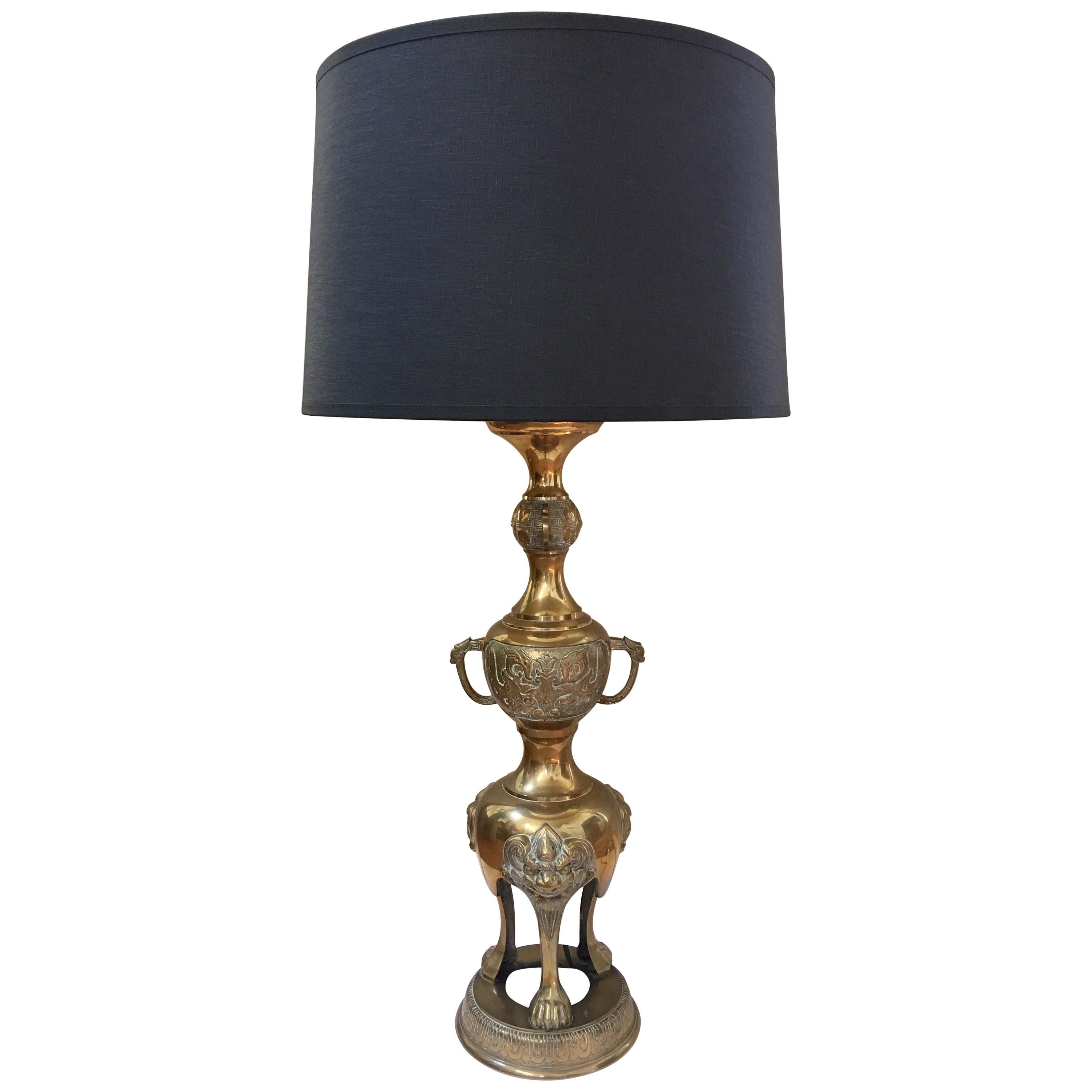 Pair of monumental and sculptural oriental style tall table lamps from the Hollywood Regency period featuring intricate carvings of the orient and foo dog heads and legs. Glamorous style of James Mont. These lighting art pieces make a great