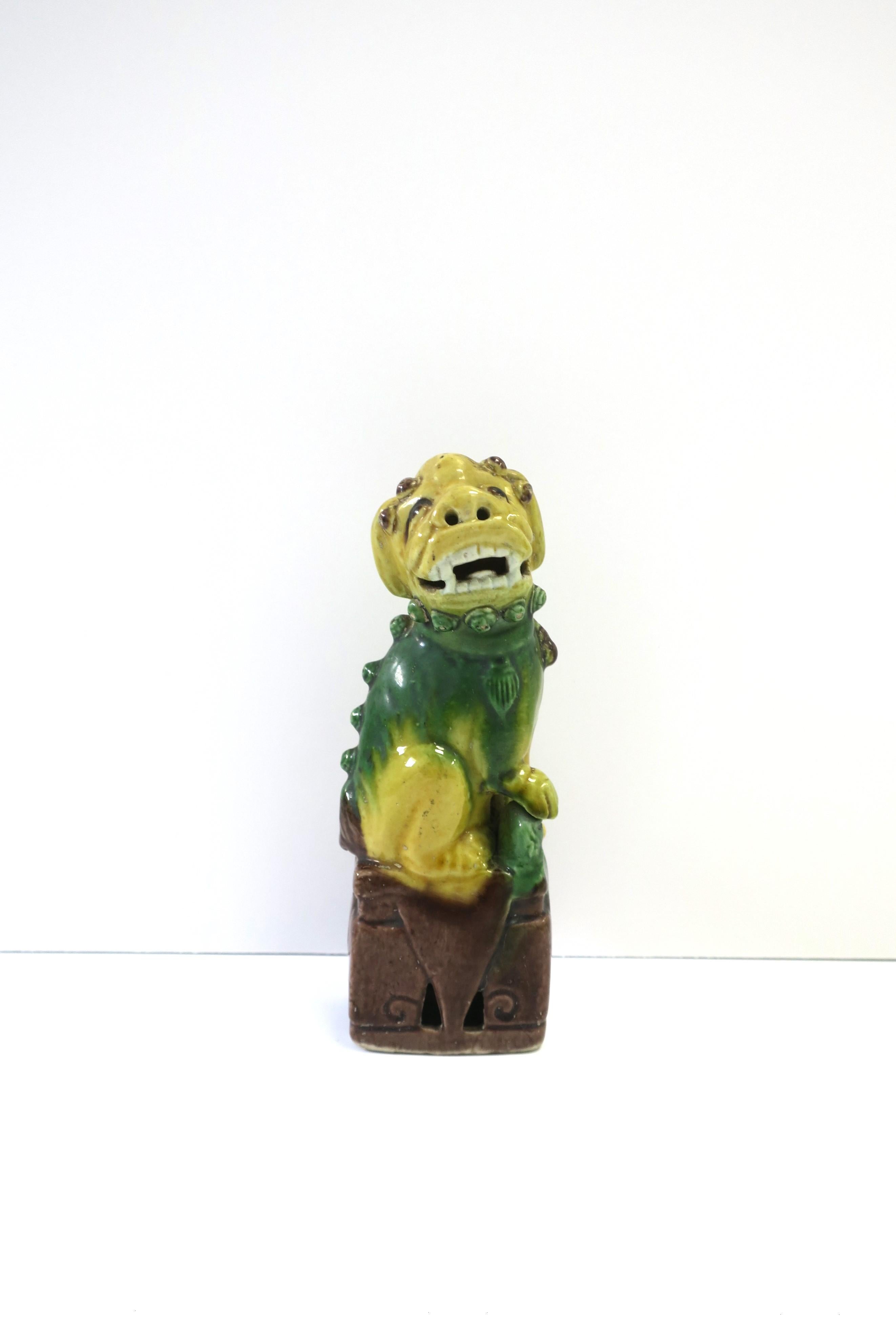 A single ceramic Lion Foo dog decorative object, circa early-20th century, 1930s, China. This Lion Foo Dog is green and yellow with dark brown accents and base. Piece and makes a great decorative object for a desk, shelf, library, cocktail table,