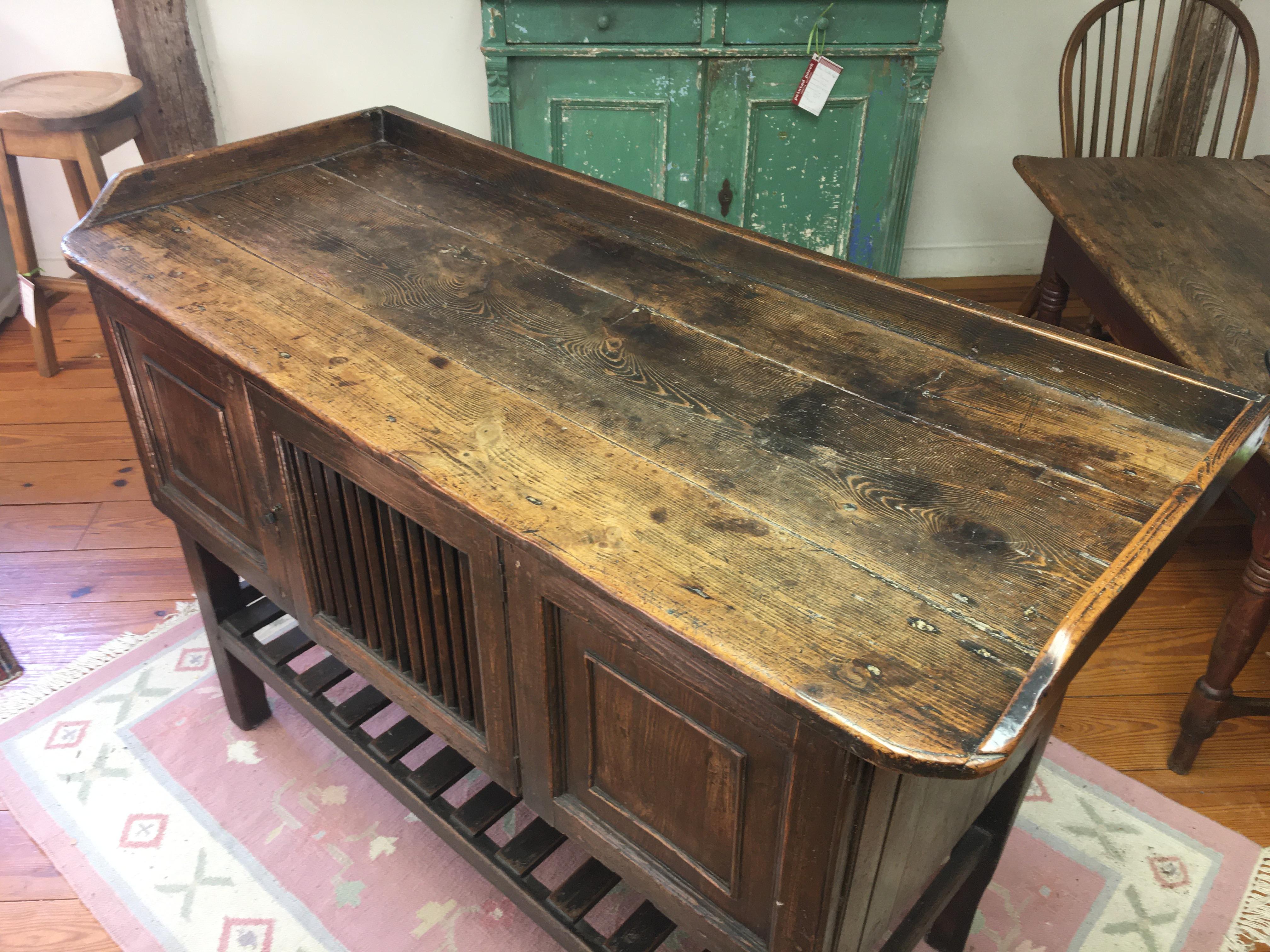 This is a total knockout, circa 1790. This piece could be used against a wall or as a free standing island. A very rich golden brown patina adorns this one of a kind piece, complete with a slatted door onto storage inside the entire length. There is