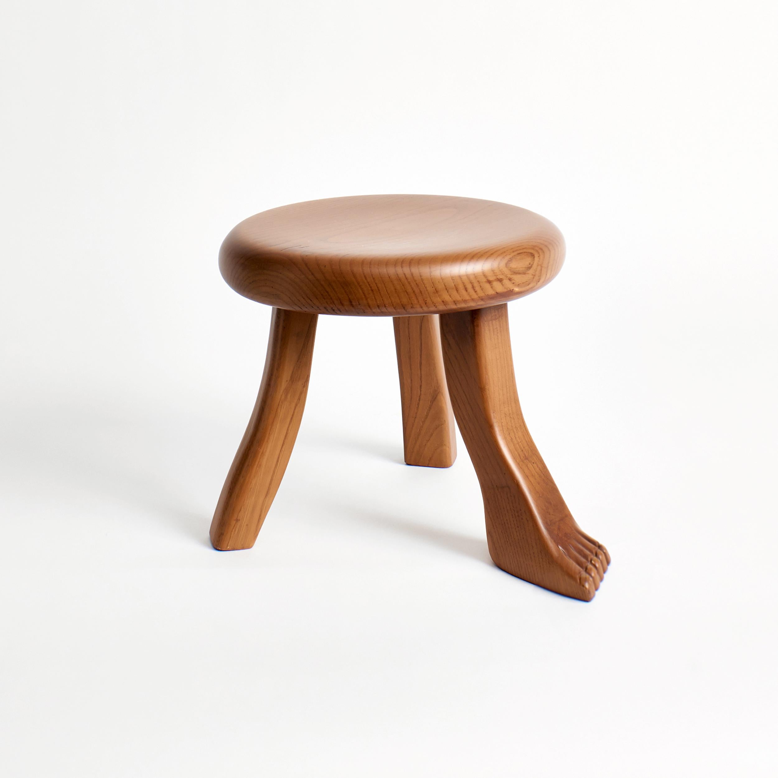 Foot stool in brown by Project 213A
Dimensions: D 30 x W 30 x H 26.5 cm
Materials: Chestnut wood. 

This playful design is inspired by a classic milking stool, and has a fun twist with three individually shaped legs. The stool is hand carved by