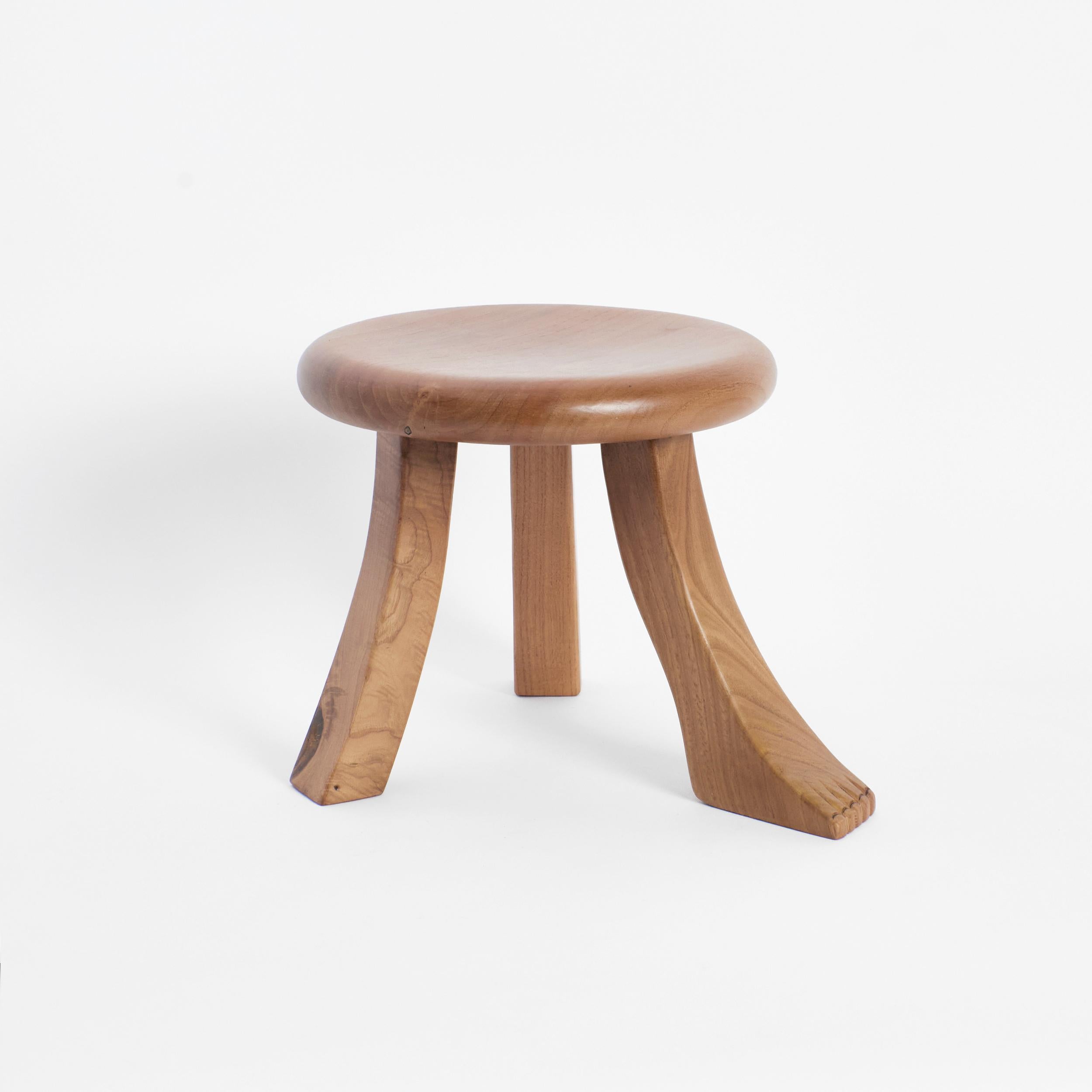 Foot stool in Natural by Project 213A
Dimensions: D 30 x W 30 x H 26.5 cm
Materials: Oak wood. 

This playful design is inspired by a classic milking stool, and has a fun twist with three individually shaped legs. The stool is hand carved by