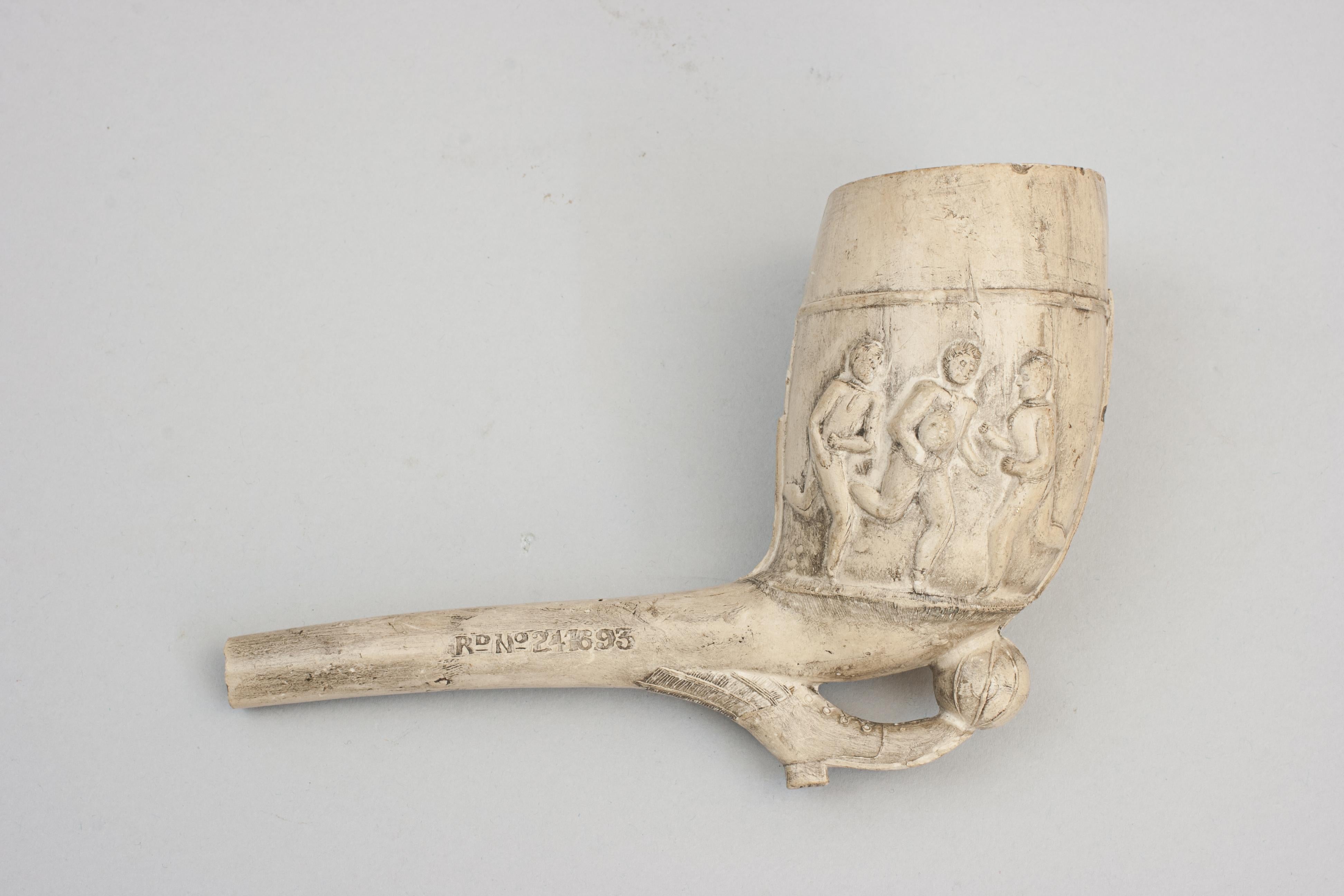 Victorian Sporting Clay Tobacco Pipe.
An early embossed Football & Rugby clay pipe. The large bowl decorated in relief with three football players on one side and three rugby players on the other, the rest being a football & boot. The stem with