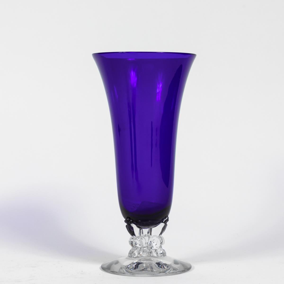 Elegant 1930s cobalt blown glass vase with clear glass pedestal foot. Known as “smalt” when ground as a pigment, cobalt glass is prepared with a cobalt compound in a glass melt. With the earnest examples dating back to 2000 BCE, cobalt smalt glass