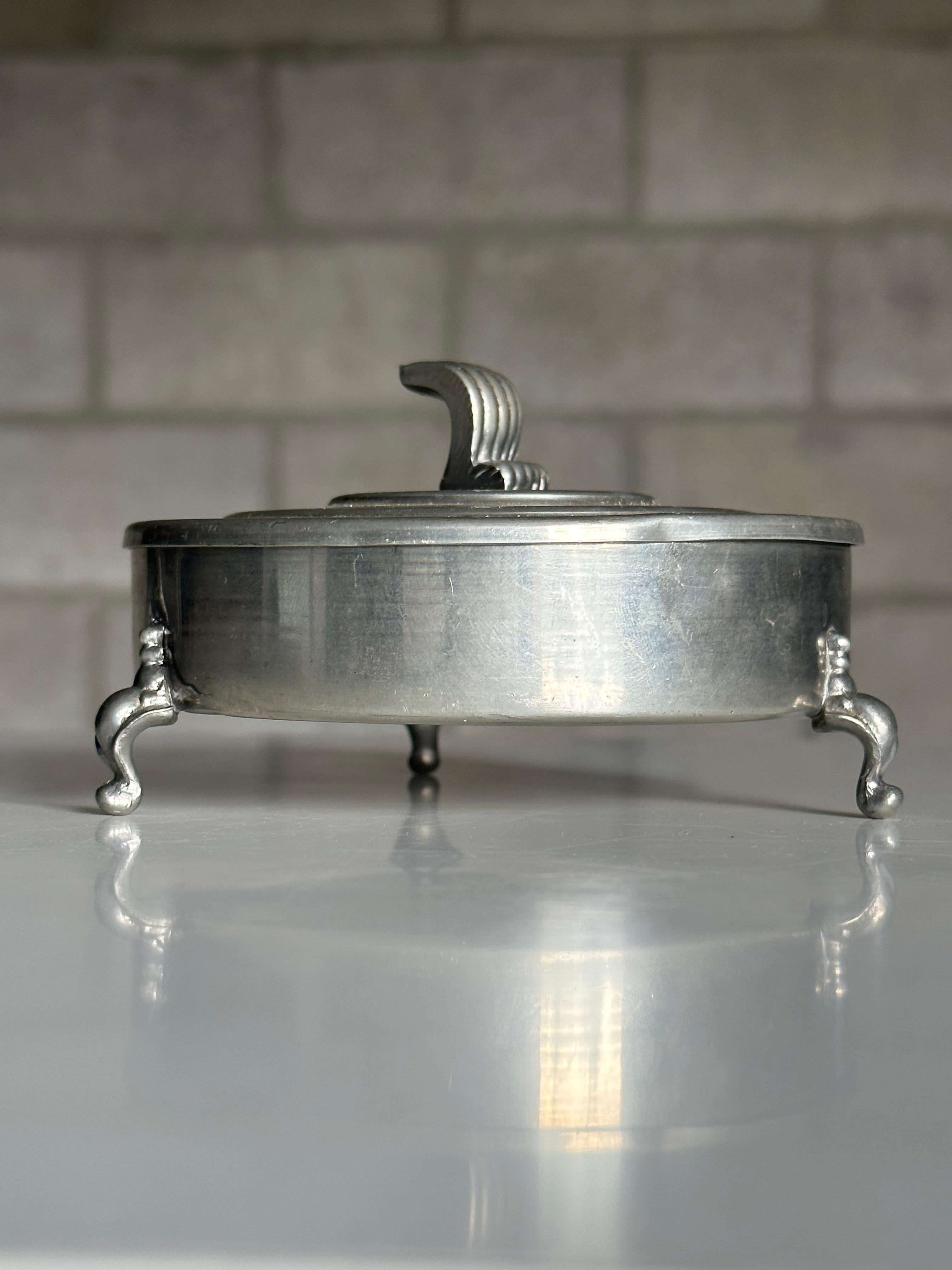 A gorgeous Art Deco pewter lidded box by Firma Svenskt Tenn. Features three ornate feet, a velvet lined interior, and Art Deco style lid.