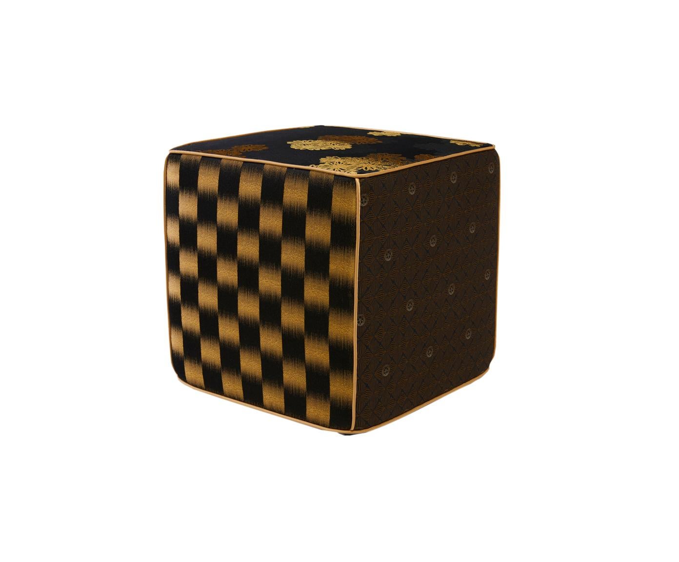 Se trata de un puf cubo de jacquard, asiento en tonos negros y dorados. Cada borde del puf está dividido por finos ribetes de satén dorado. Los distintos motivos de los laterales del puf están bellamente diseñados con racimos de flores en 3D y