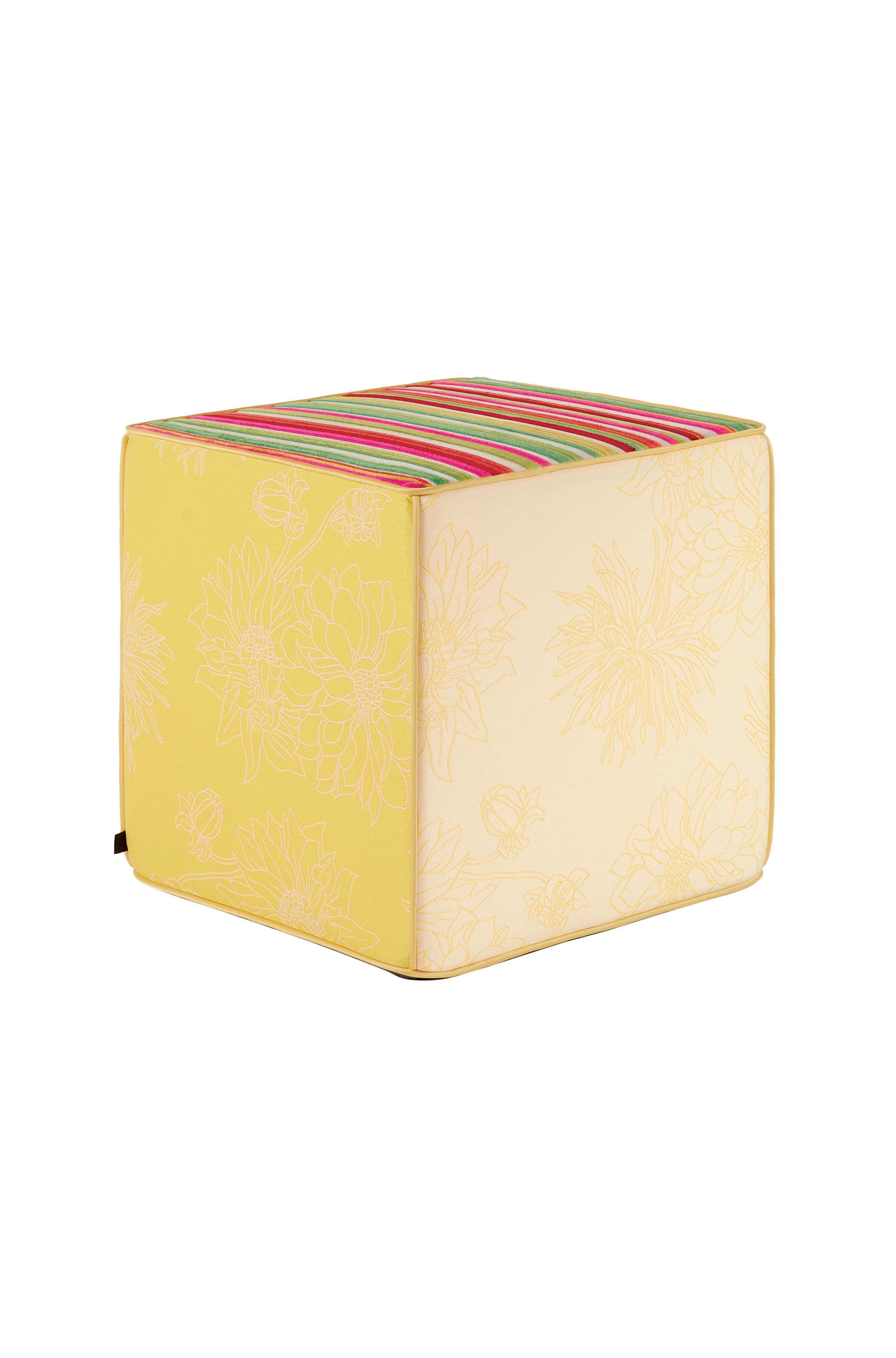 Se trata de un puf cubo de jacquard, asiento en un vibrante tono amarillo. Los laterales del puf presentan un juguetón estampado floral en colores invertidos y la parte superior del puf está diseñada con elegantes rayas de terciopelo en 3D en los