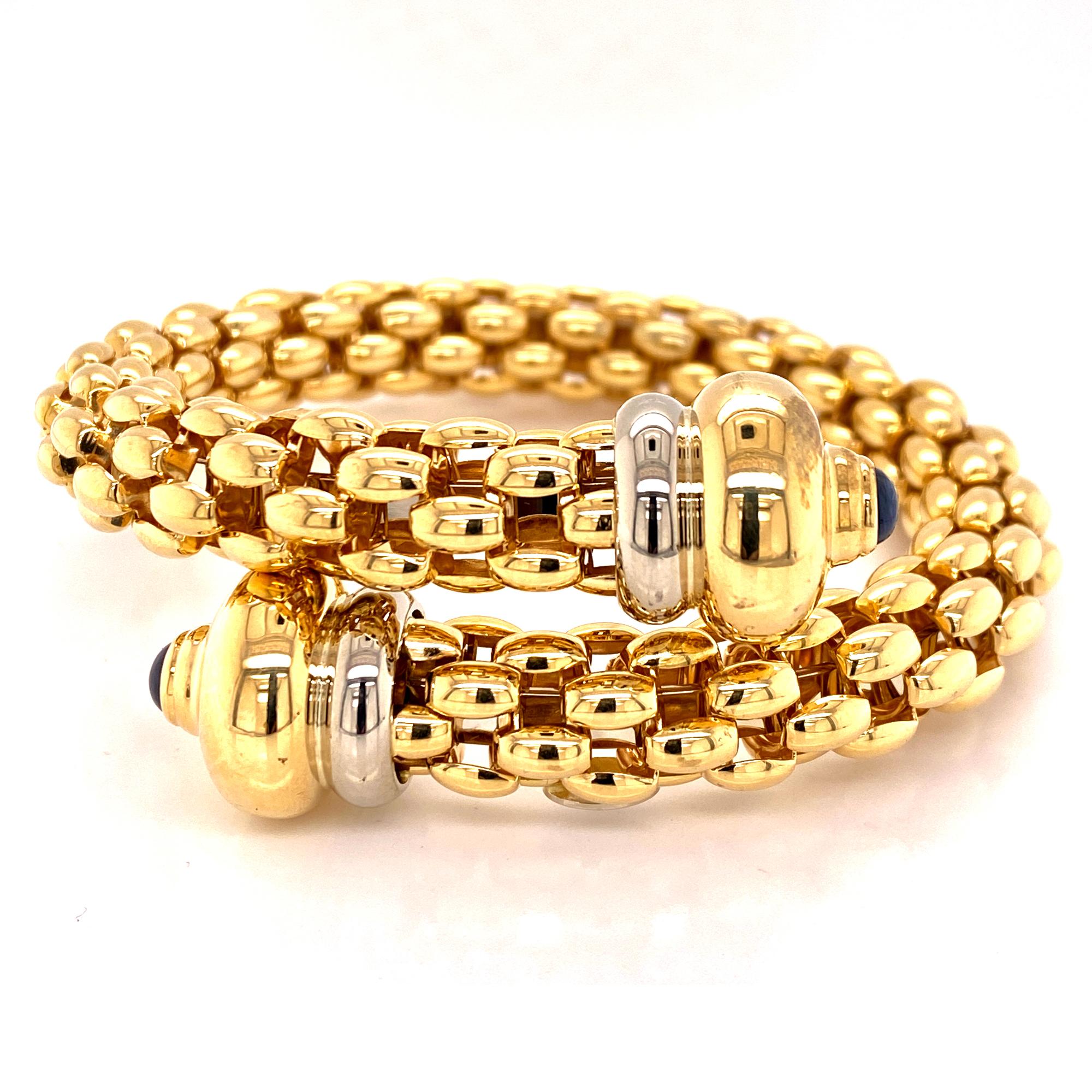 Italian 18 karat gold coil bracelet by designer Fope. The flexible bracelet features cabochon sapphire endcaps. The bracelet measures 2.25 inches in diameter and can fit many wrist sizes.