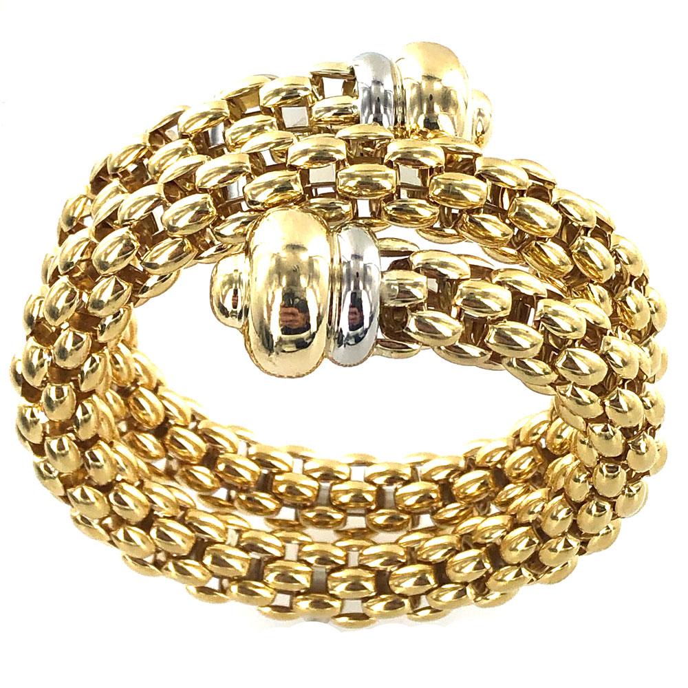 Fope coil bracelet fashioned in 18 karat yellow gold. The end caps are crafted with 18 karat white and yellow gold. The bracelet can fit multiple wrist sizes secondary to its flexible nature. All together it measures 1.50 inches in width, and 2.00