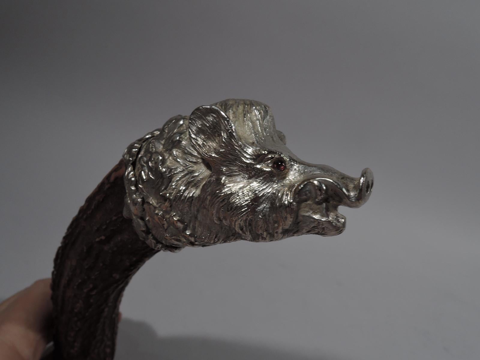 Antique hunter's cigar cutter, circa 1920. Irregular and corrugated horn handle. Mounted to one end is silver boar’s head—all bristly fur, perked ears, alert snout, and red glass bead eyes. Oakleaf collar. At other end is mounted the hardware with