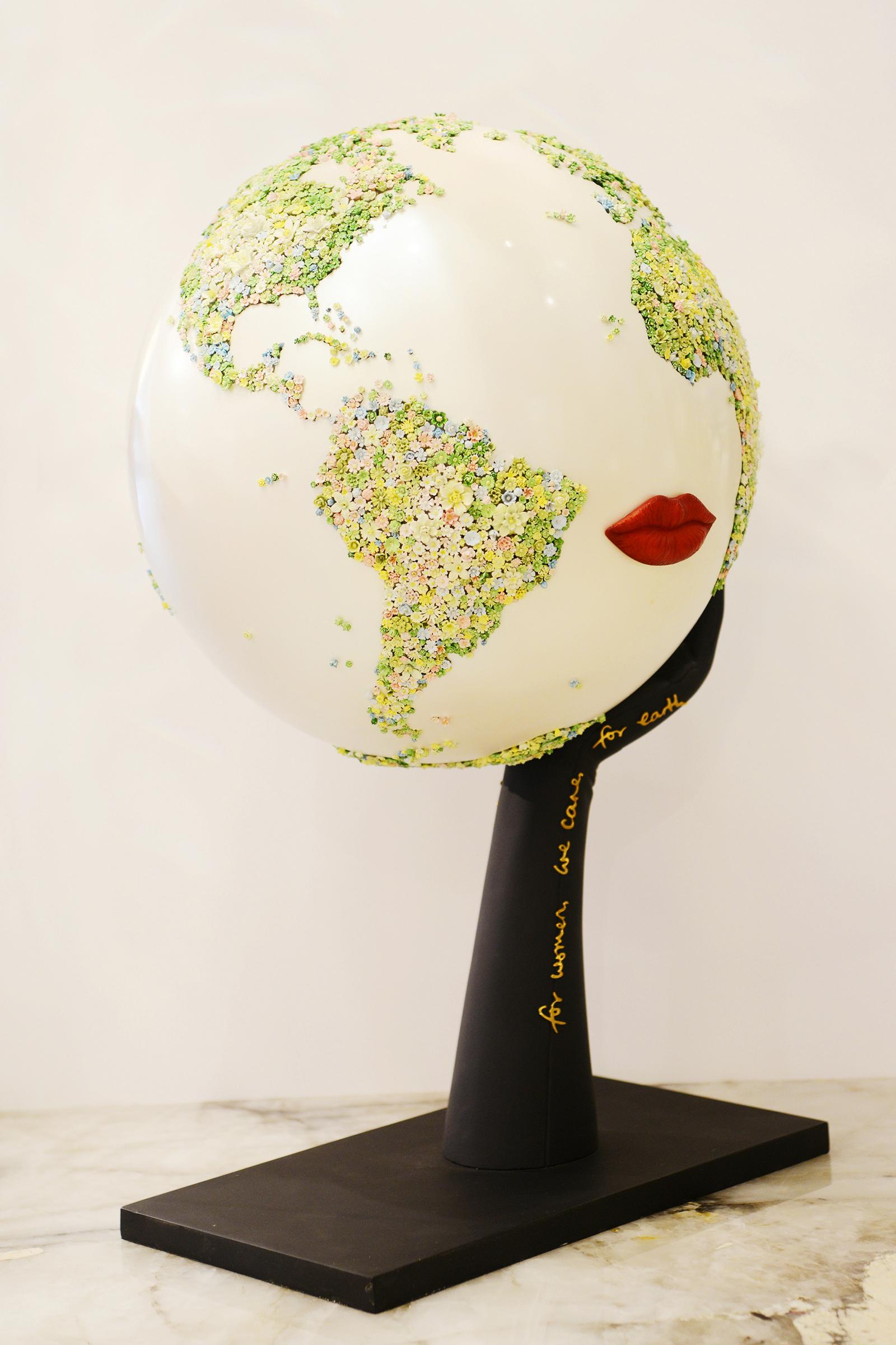 Globe For Women We Care for Earth Green, la structure du globe 
est en résine avec une finition blanc nacré et un décor floral de 
3 000 pièces peintes. Les lèvres rouges sont en galalithe sculptée. 
La base est en métal avec une finition noire