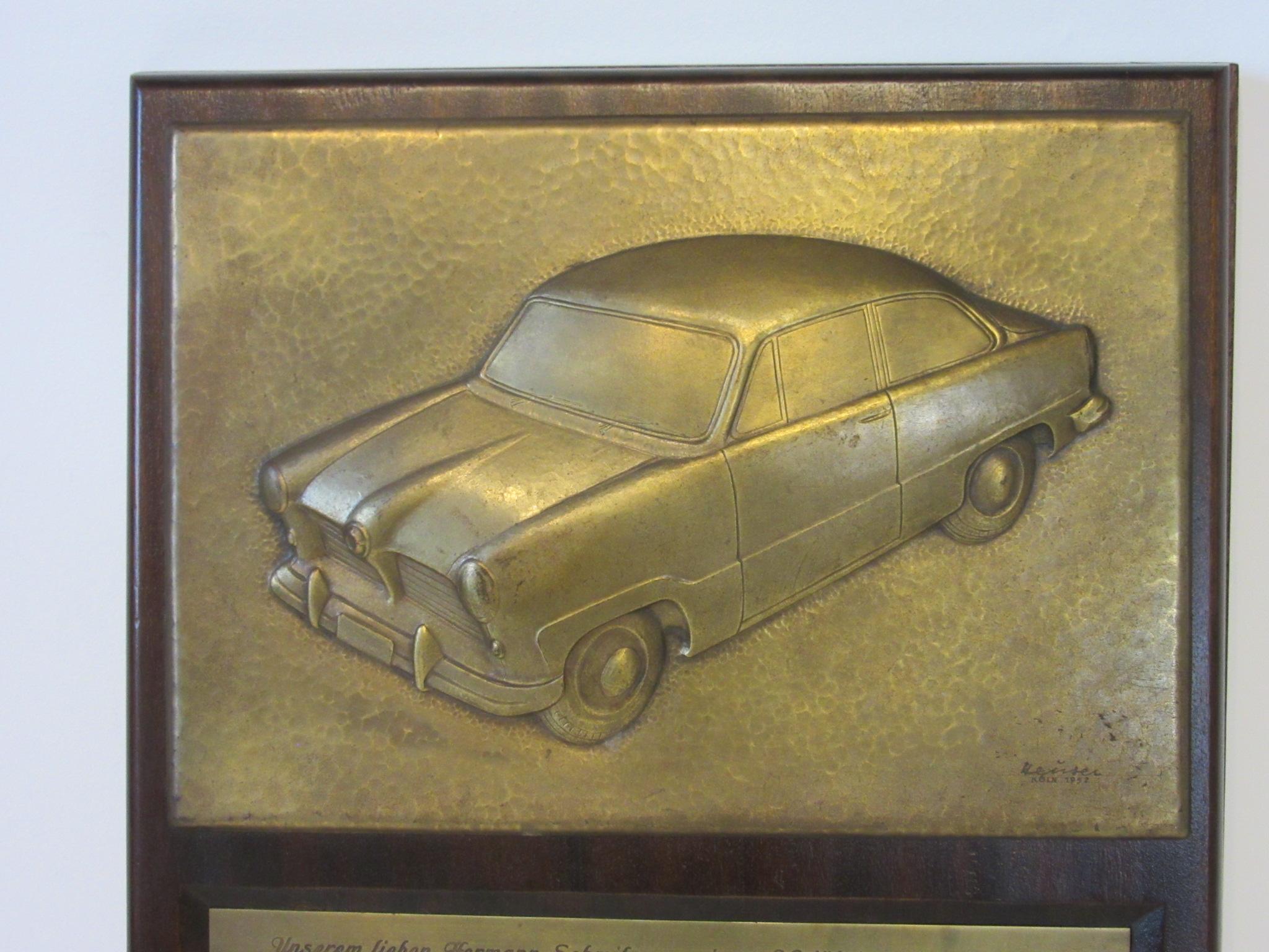 A Handcrafted ford factory commemorative plaque for the Taunus automobile manufactured in Germany celebrating the 30th anniversary of chief designer Herman Schmtz. Hand hammered bronze toned metal relief of the car signed and dated by the artist 