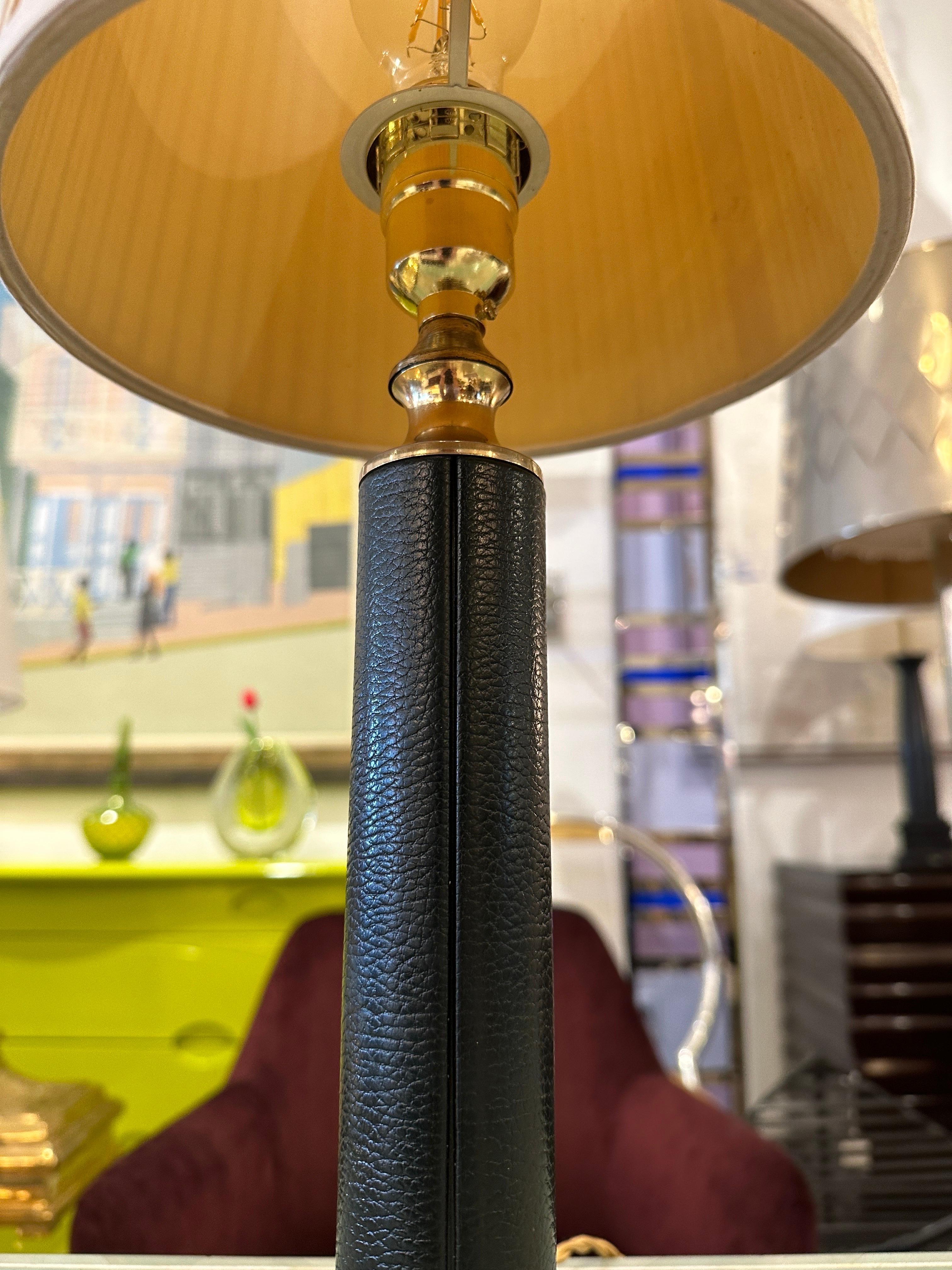 Reminiscent of Paul Dupre-Lafon, this rich green leather clad cylinder lamp with brass accents has been newly updated with new socket and cotton twisted cord. Vintage pleated shade is included.  THIS ITEM IS LOCATED AND WILL SHIP FROM OUR EAST