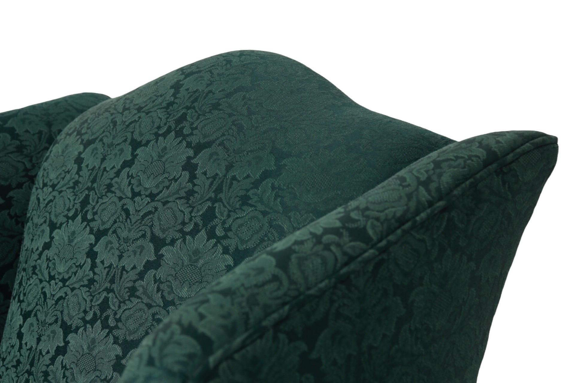 A pair of Queen Anne style wingback chairs made by Carolina Custom Furniture. Upholstered throughout in a forest green damask fabric with a floral motif. Cabriole legs finish in rounded pad feet. Dimensions per chair. Arm height 24.5