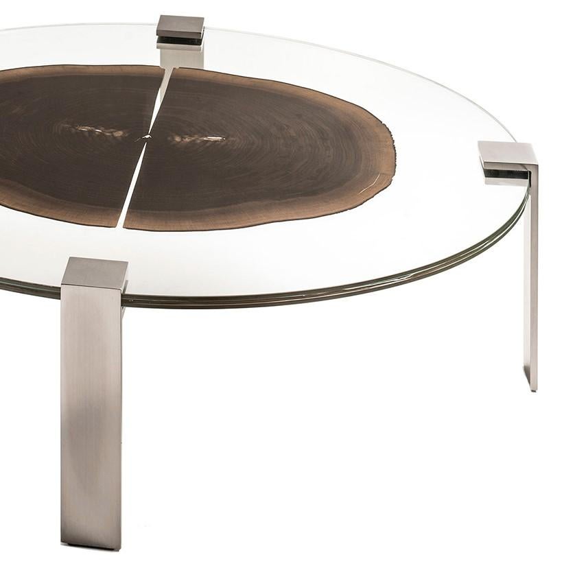 This striking coffee table is part of the glass and wood collection and is made of two layers of glass that contain a thin section of a tree slice. The uniqueness of the piece of wood and its striking natural veins add a one-of-a-kind quality to it.