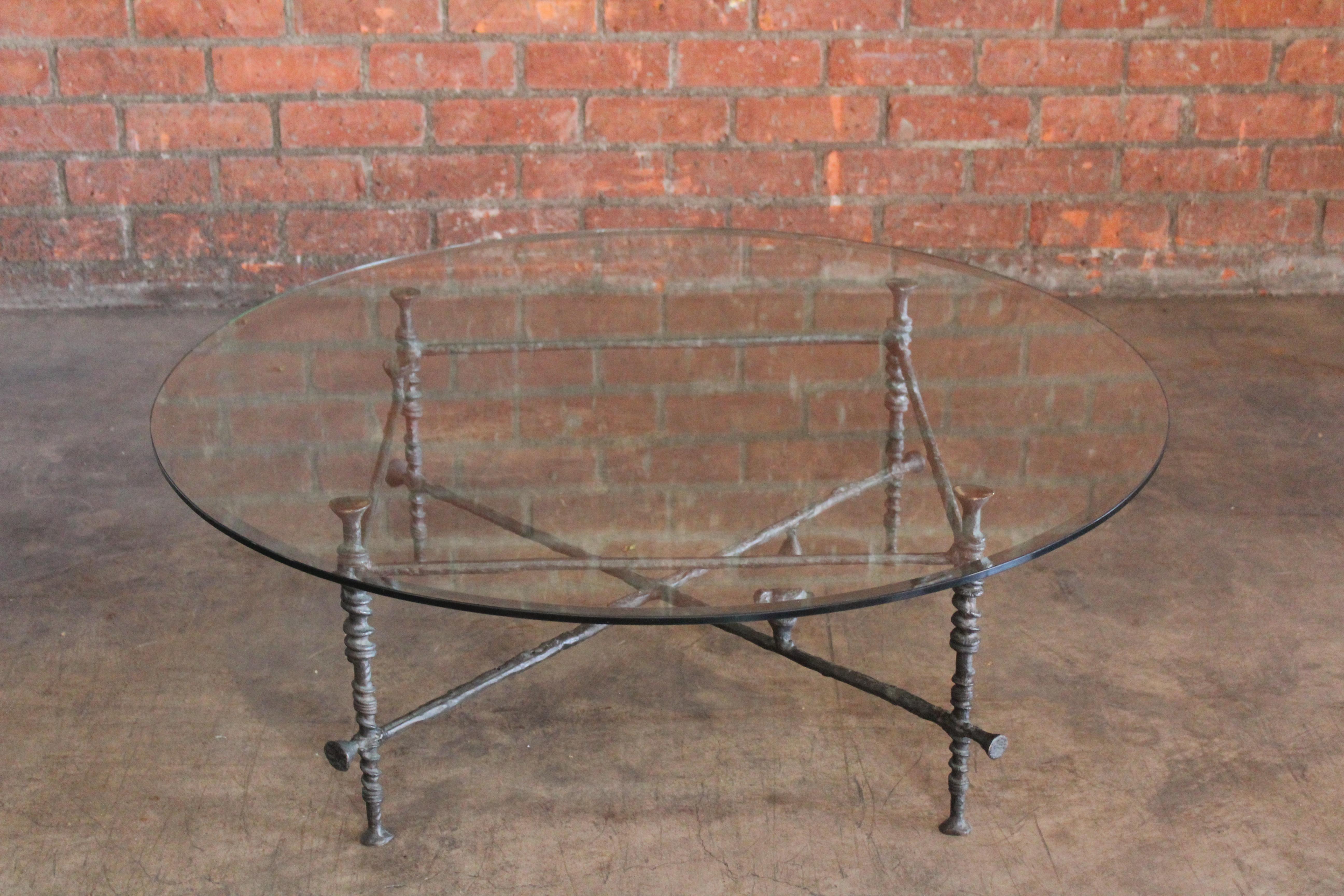 A vintage forged bronze coffee table in the manner of Diego Giacometti. New tempered glass top with beveled edge.