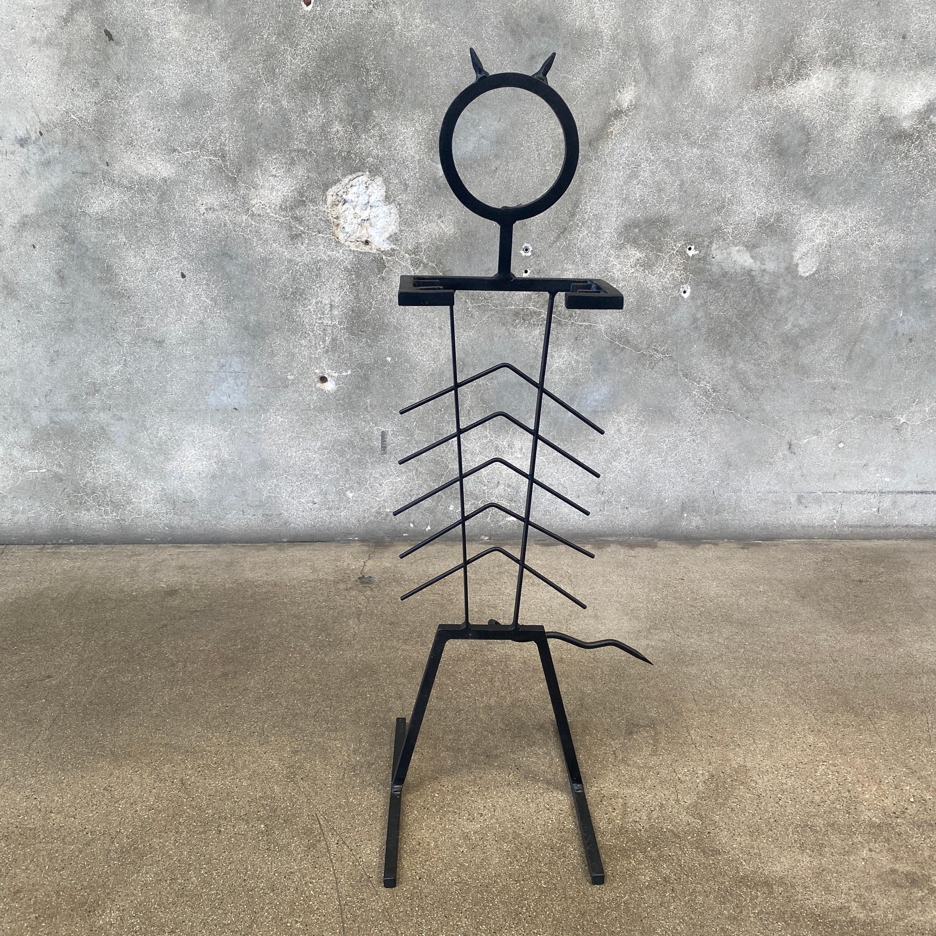 This is a one of a kind fireplace tools set that is signed MAN MADE 89. The holder itself is a piece of art and resembles a creature with head, arms, legs, body, and a tail. The arms extend to embrace 4 different tools including a shovel, poker,